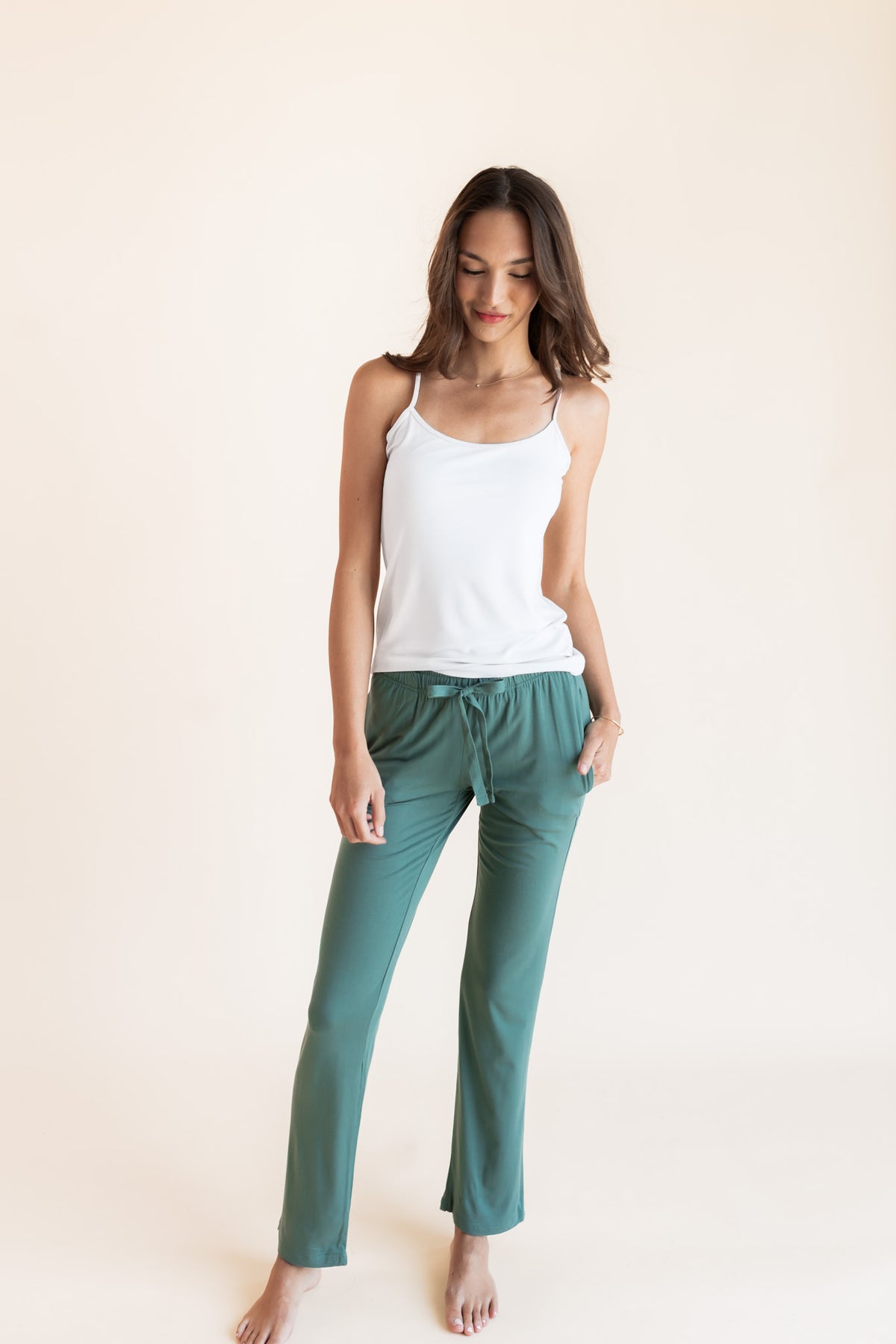 Model posing in Women's Lounge Pants in Pine under white camisole on a beige background