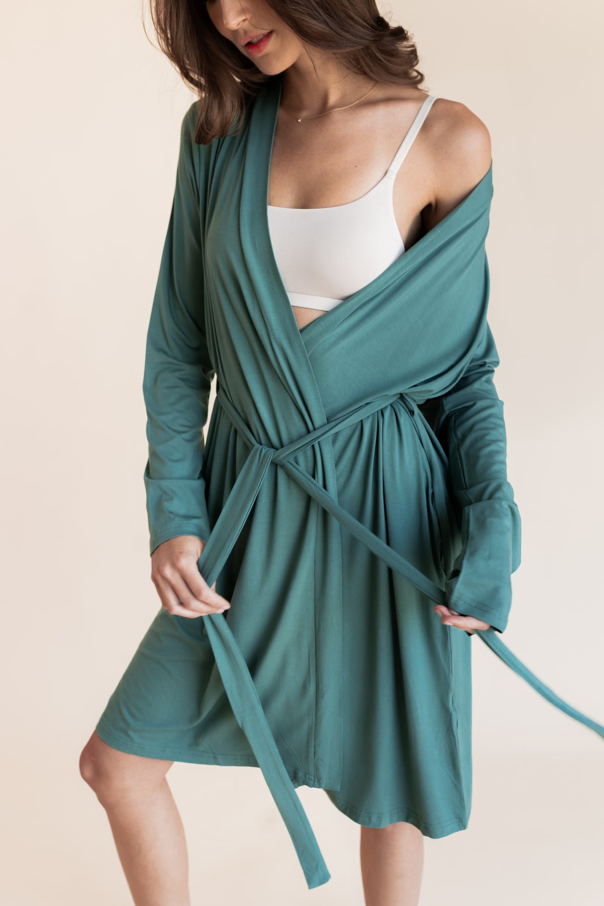 Close up of Model wearing Women's Lounge Robe with belt in Pine over white bralette on a beige background