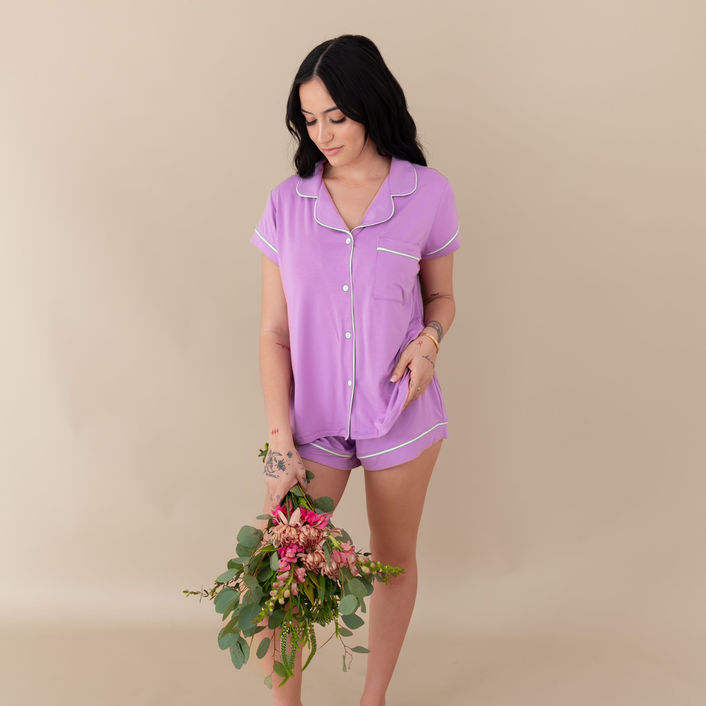 Woman modeling Women’s Short Sleeve Pajama Set in Poi with Cloud Trim holding a bouquet of flowers.