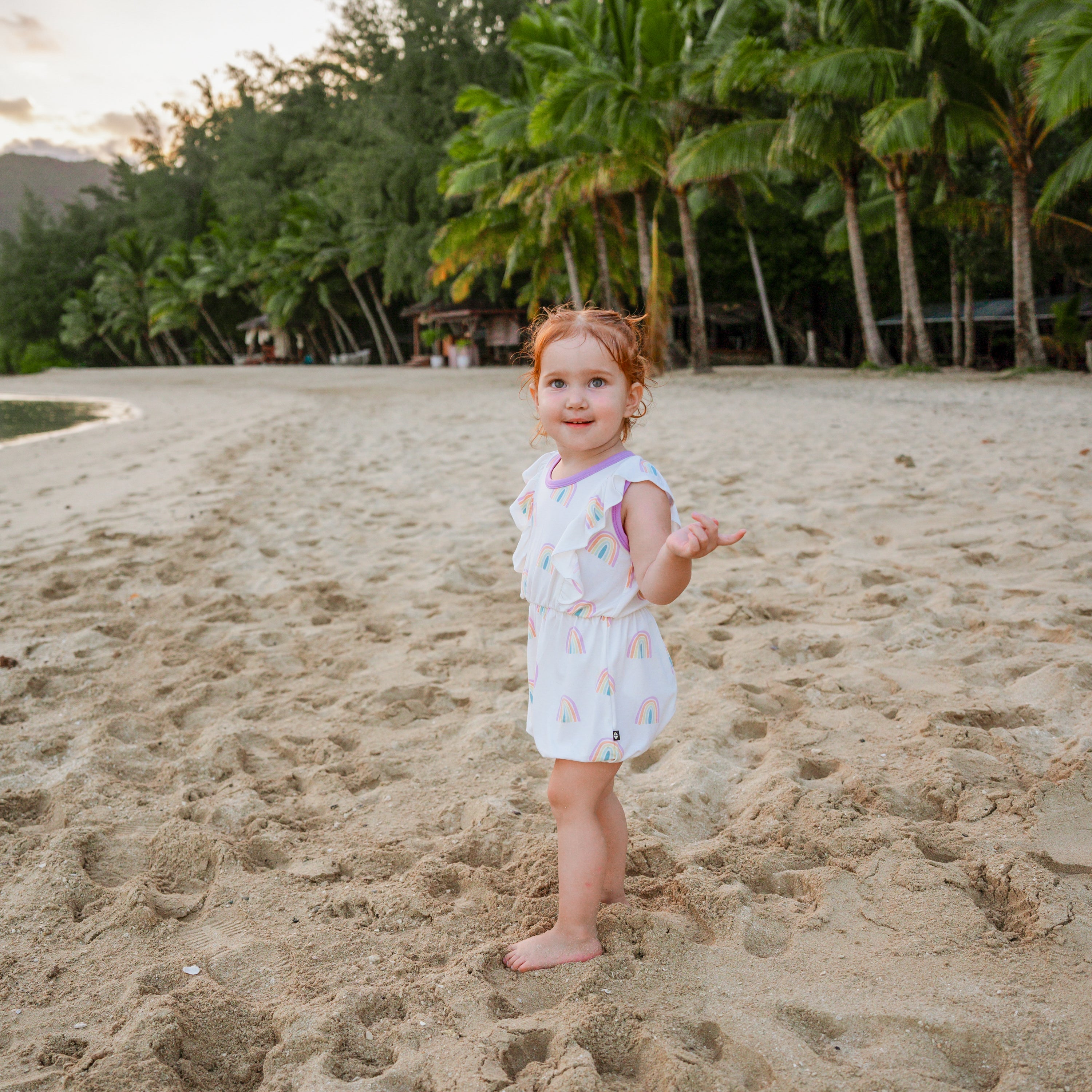 Toddler wearing Bubble Romper in Poi Rainbow on the beach