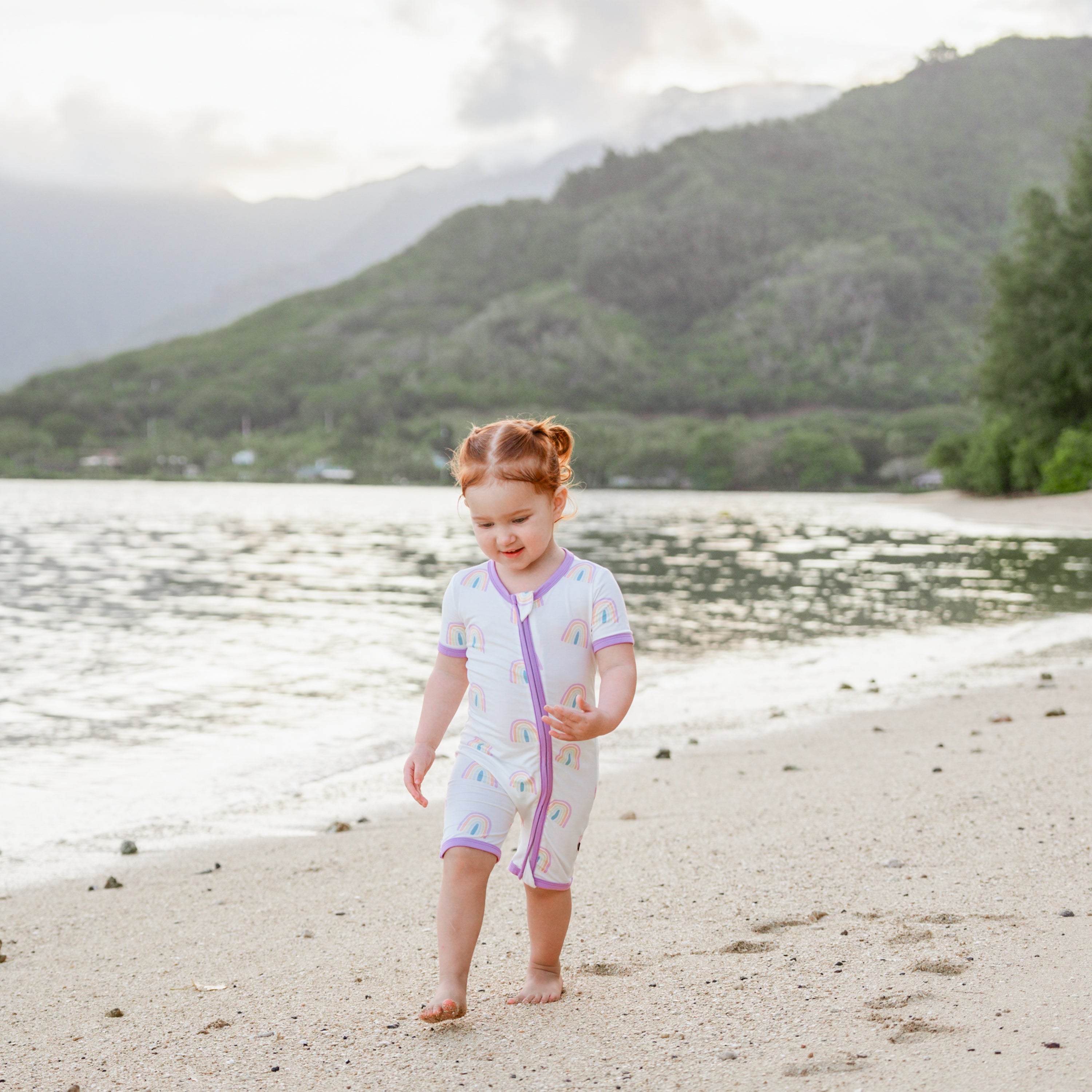 Toddler wearing bamboo Kyte Baby Zippered Shortall Romper in Poi Rainbow