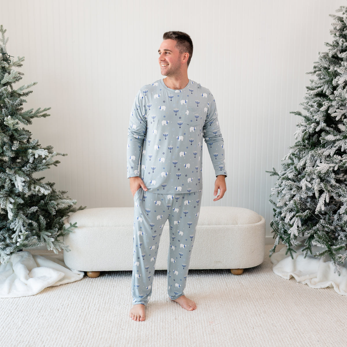 Male model standing in front of a cream ottoman between two frosted trees wearing the Men's Jogger Set in Polar Lights