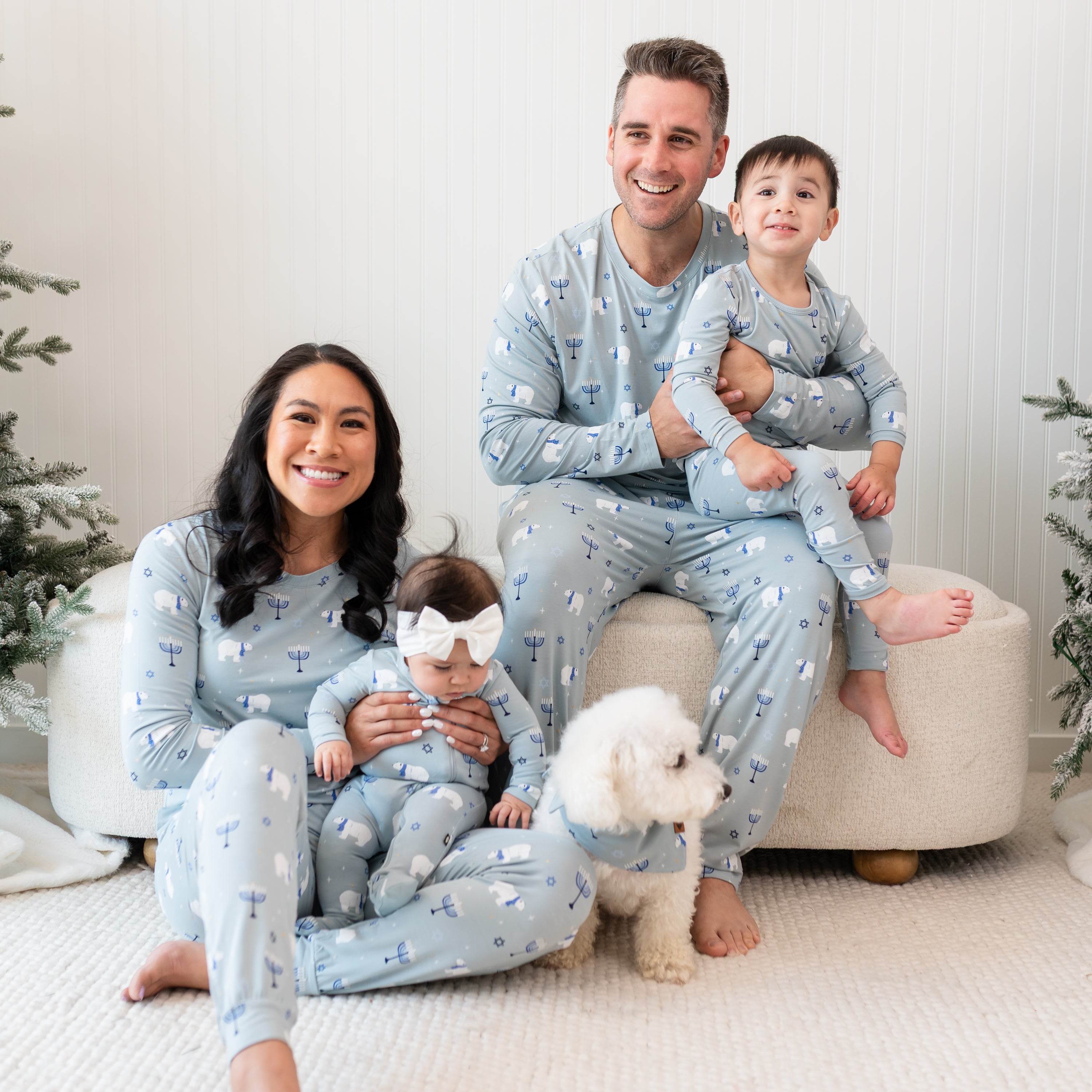Family of four sitting and matching in the Polar Lights print with small white dog sitting on the floor wearing the Dog Bandana in Polar Lights