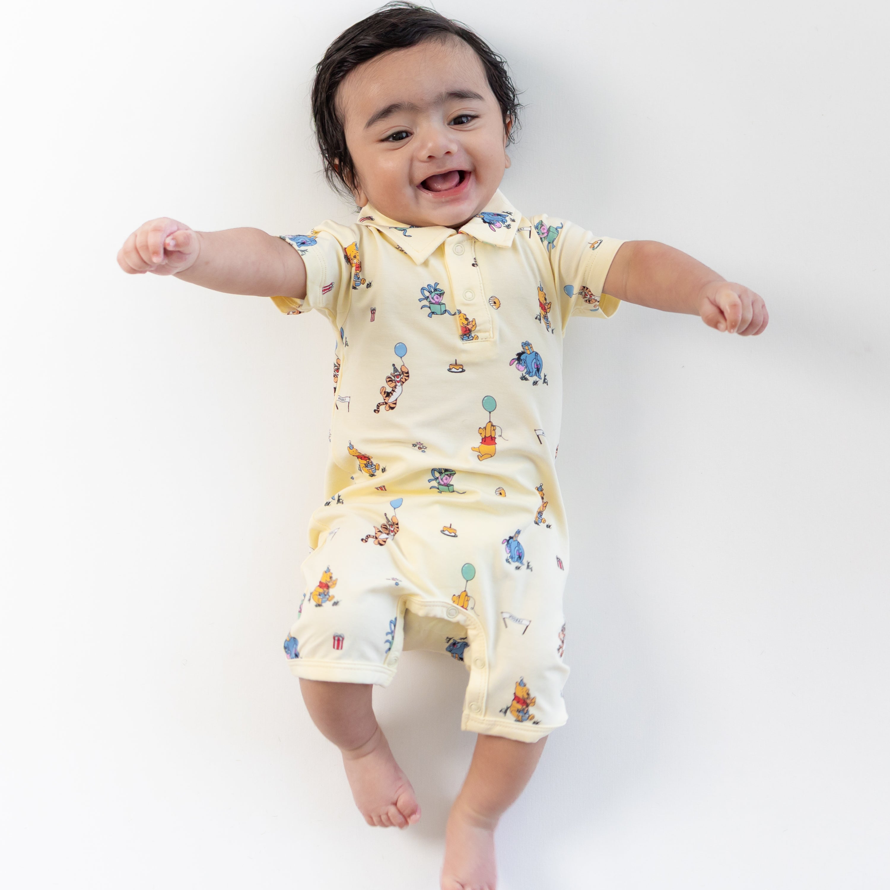 Young smiling toddler wearing the Polo Shortall in Winnie the Pooh Celebration