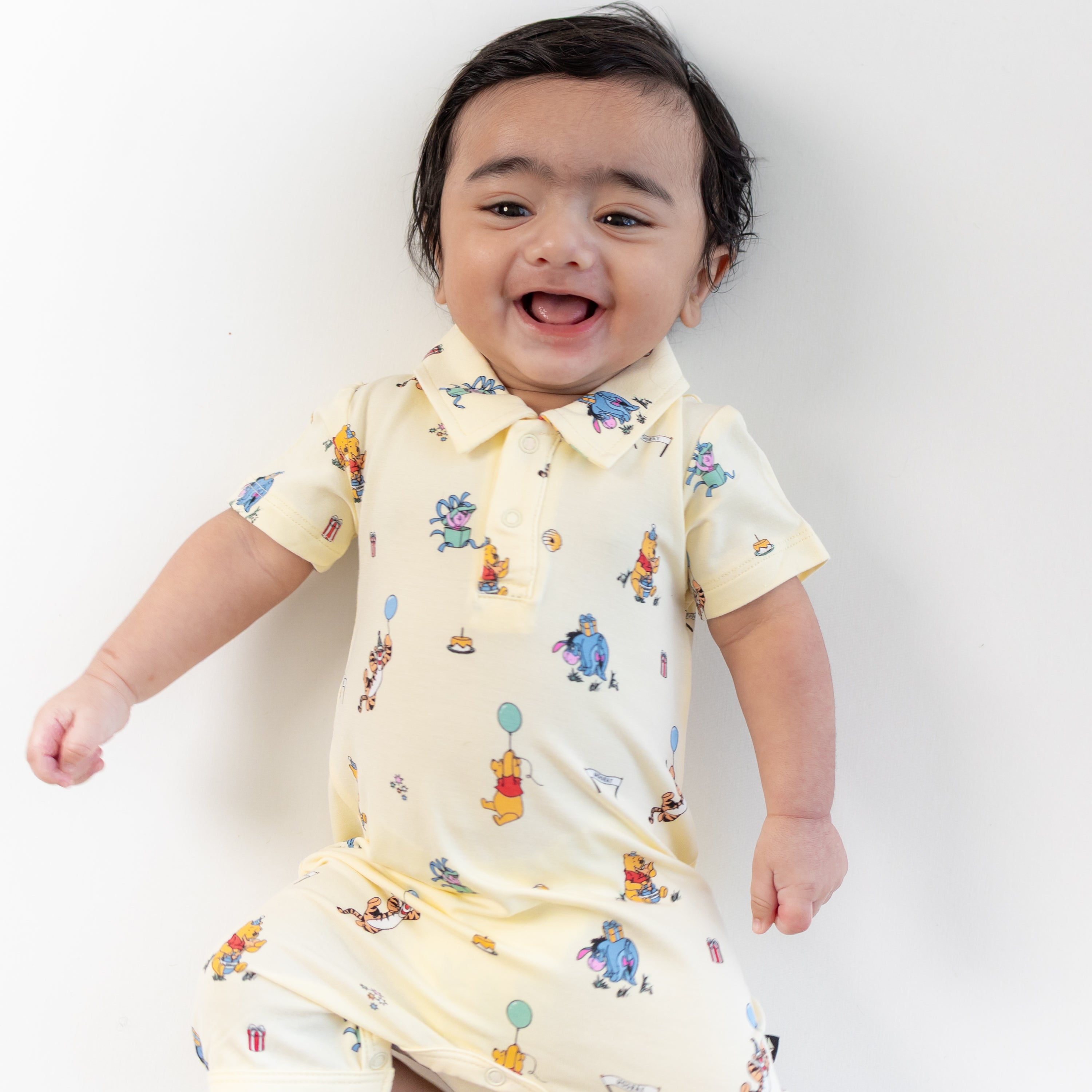 Close up of smiling toddler wearing the Polo Shortall in Winnie the Pooh Celebration