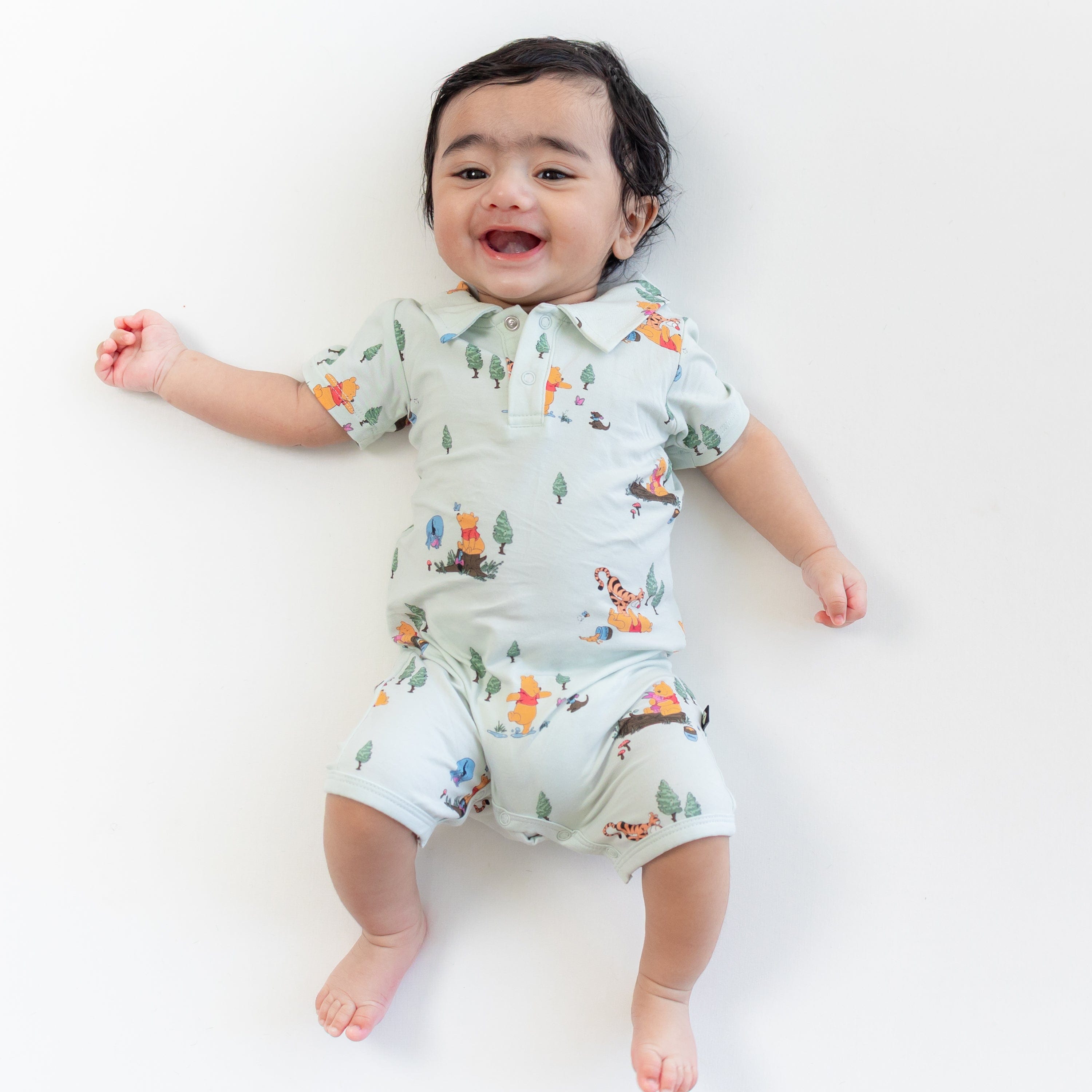 Smiling toddler wearing the Polo Shortall in Winnie the Pooh Hundred Acre Wood