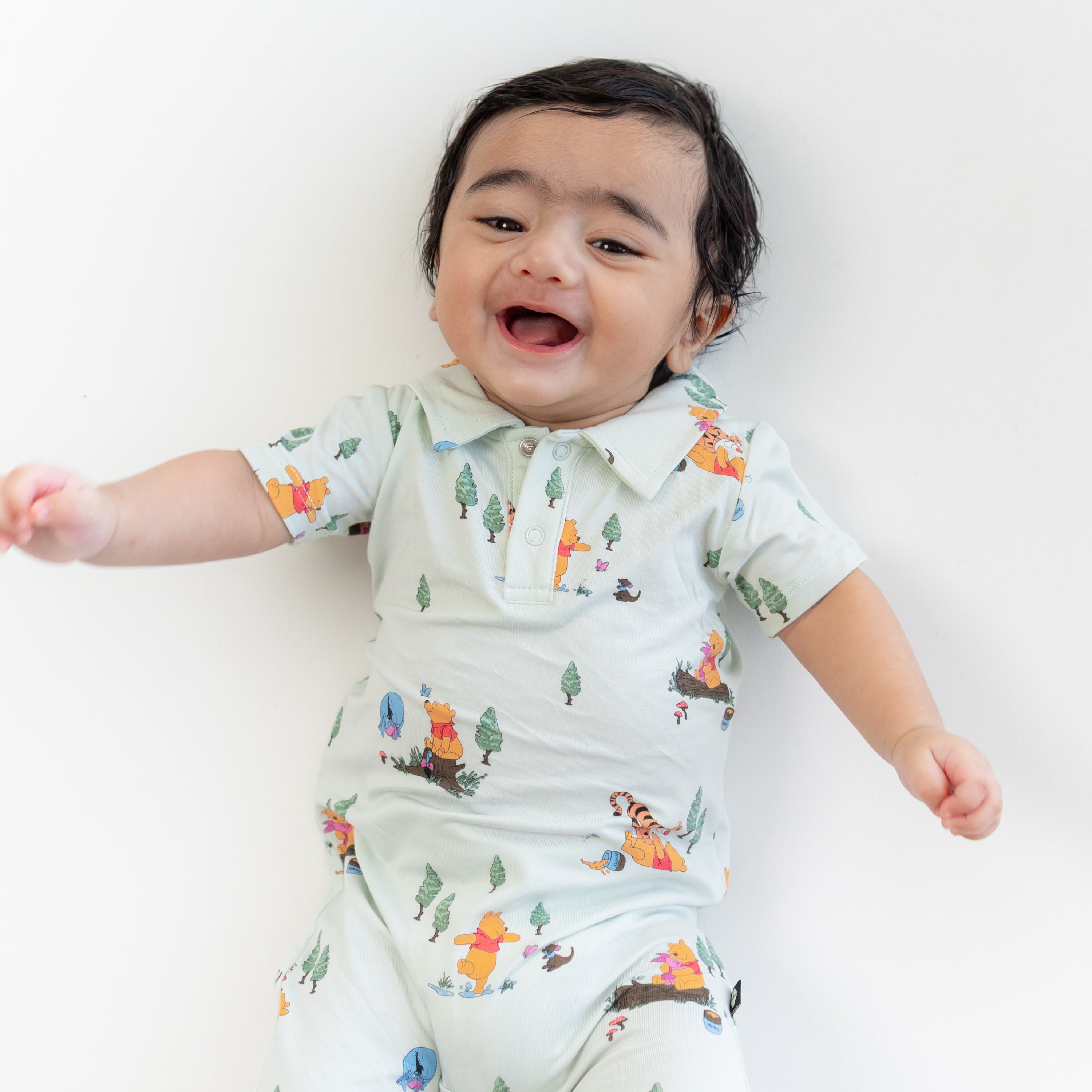Close up of smiling toddler wearing the Polo Shortall in Winnie the Pooh Hundred Acre Wood