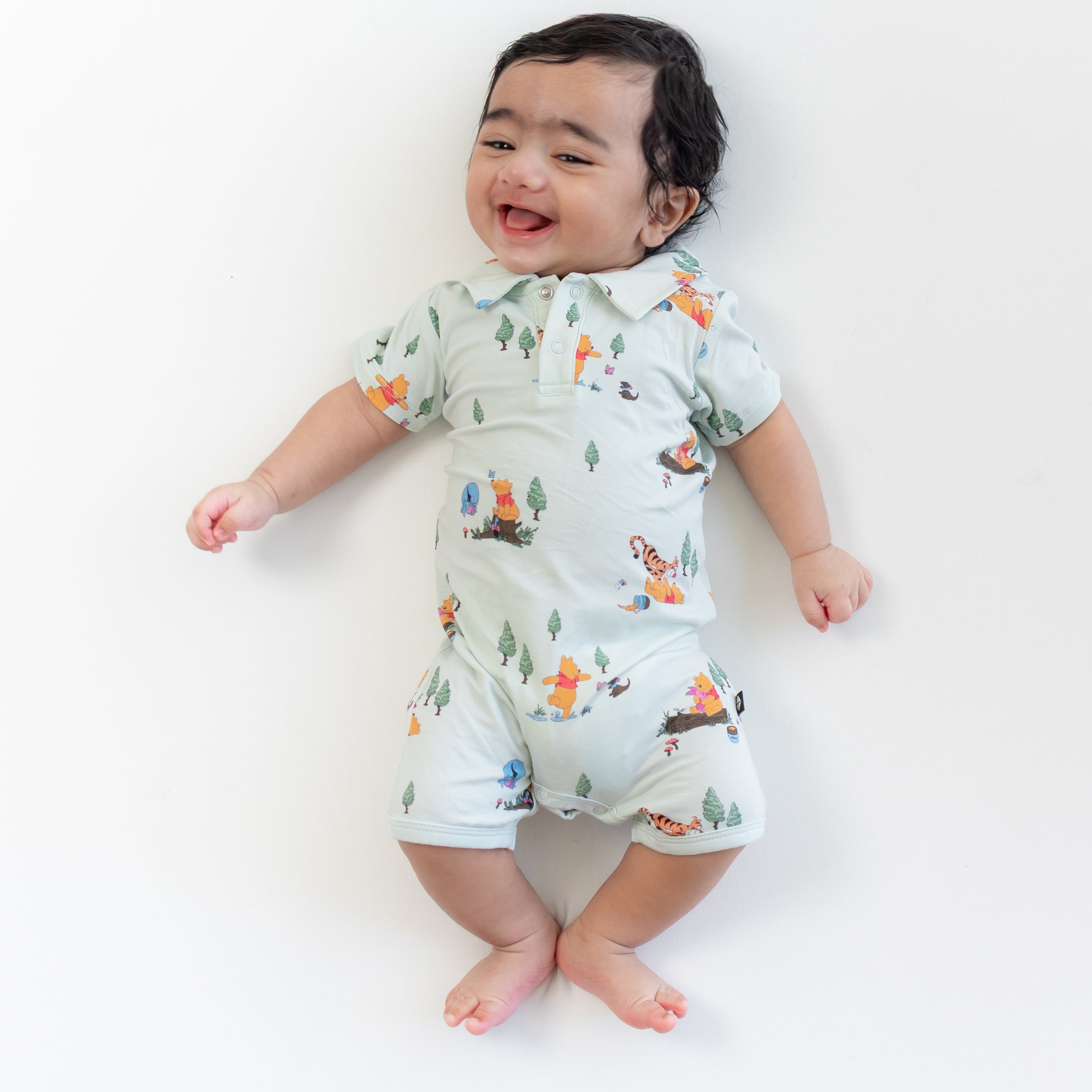 Smiling infant wearing the Polo Shortall in Winnie the Pooh Hundred Acre Wood