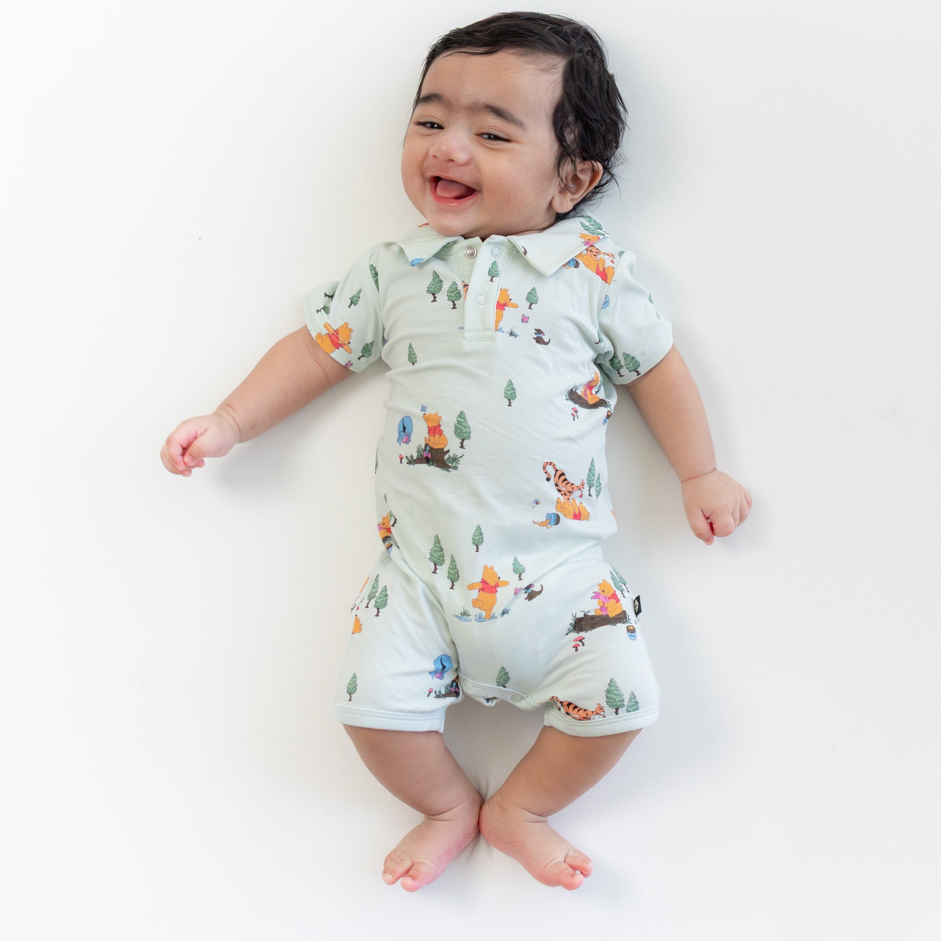 Smiling infant wearing the Polo Shortall in Winnie the Pooh Hundred Acre Wood