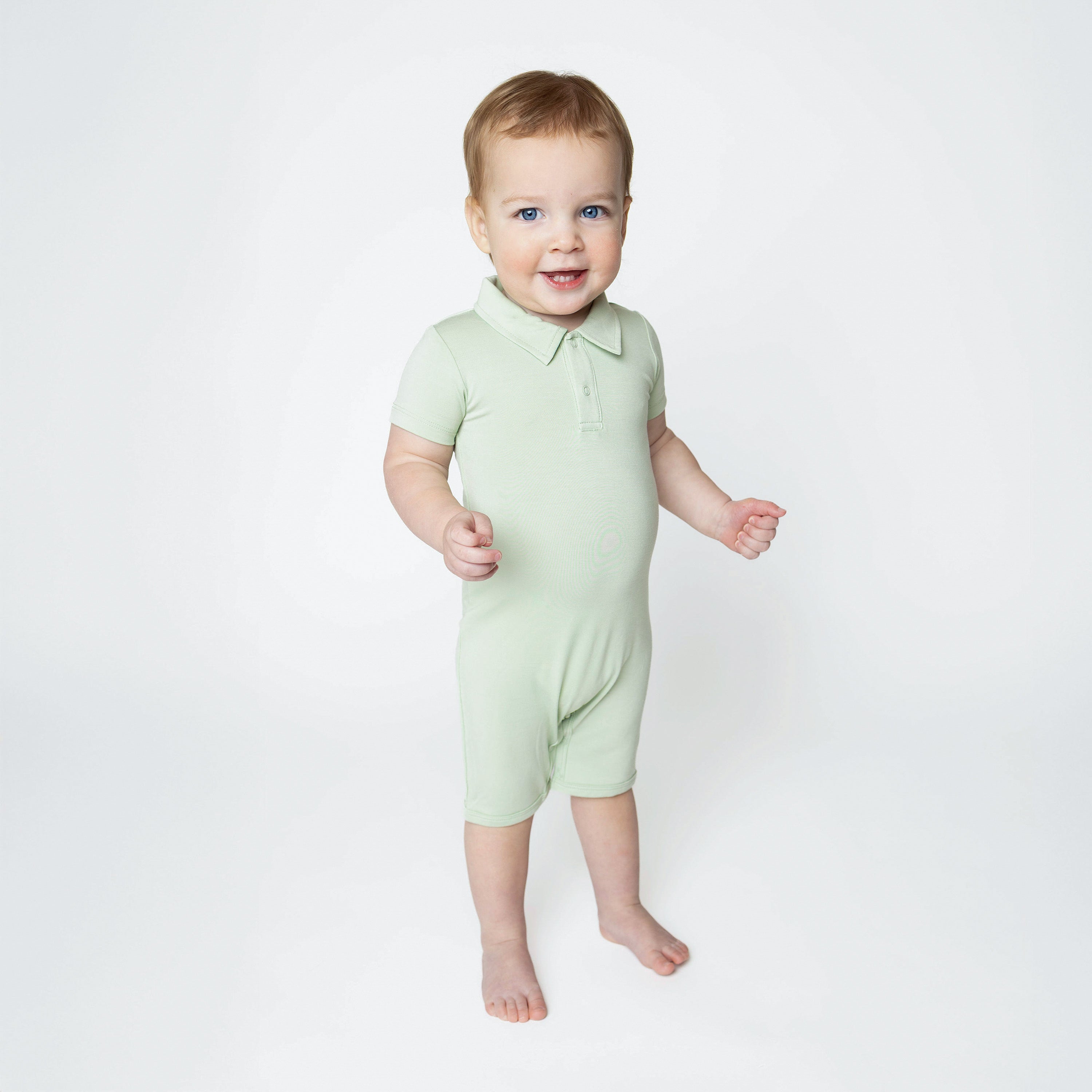 Young toddler standing in front of a white background wearing the Polo Shortall in Basil
