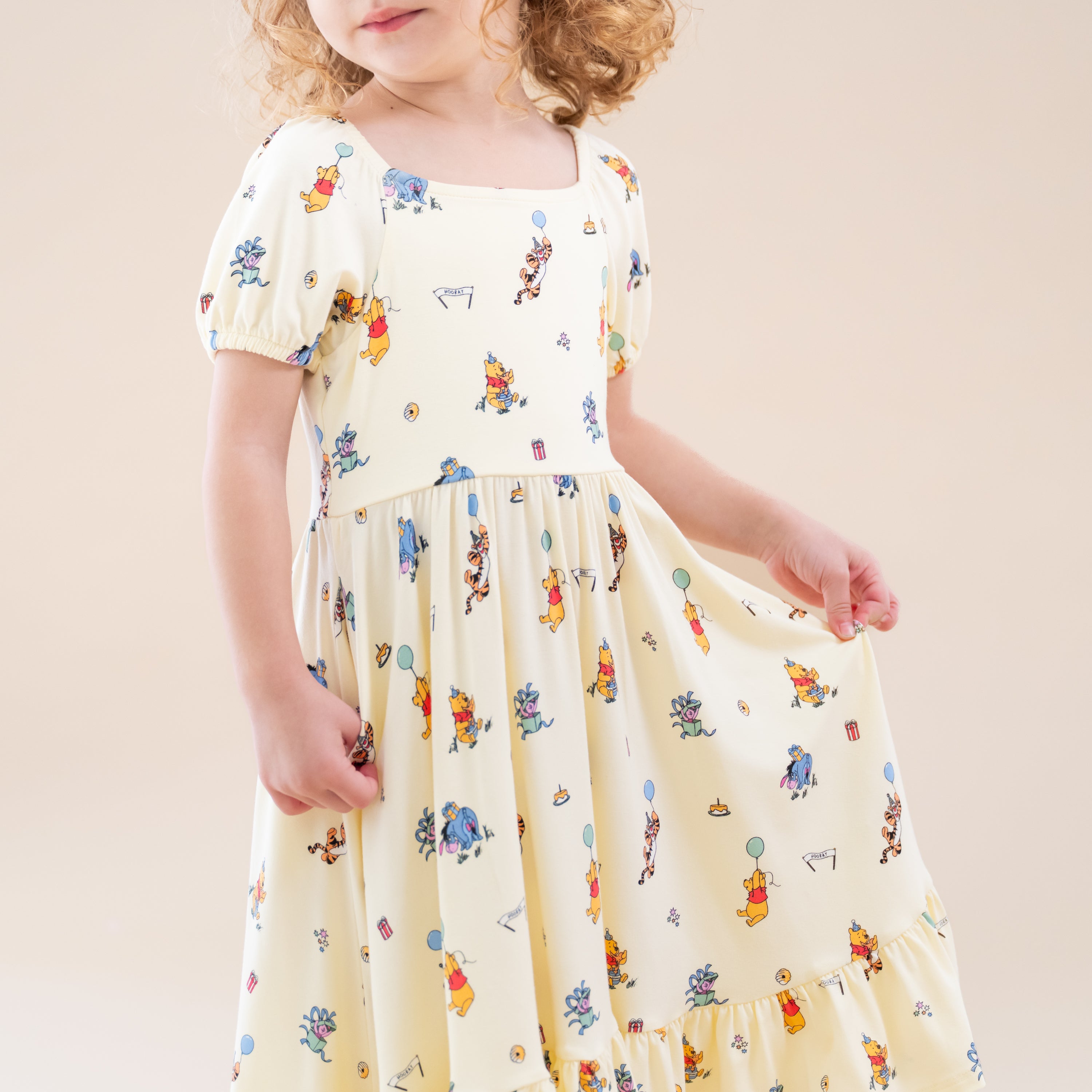 Close up of the Puff Sleeve Twirl Dress in Winnie the Pooh Celebration shown on a young girl