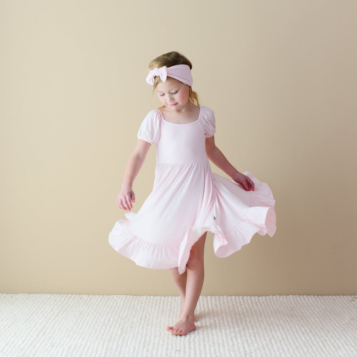 Girl wearing Puff Sleeve Twirl Dress in Sakura Pink