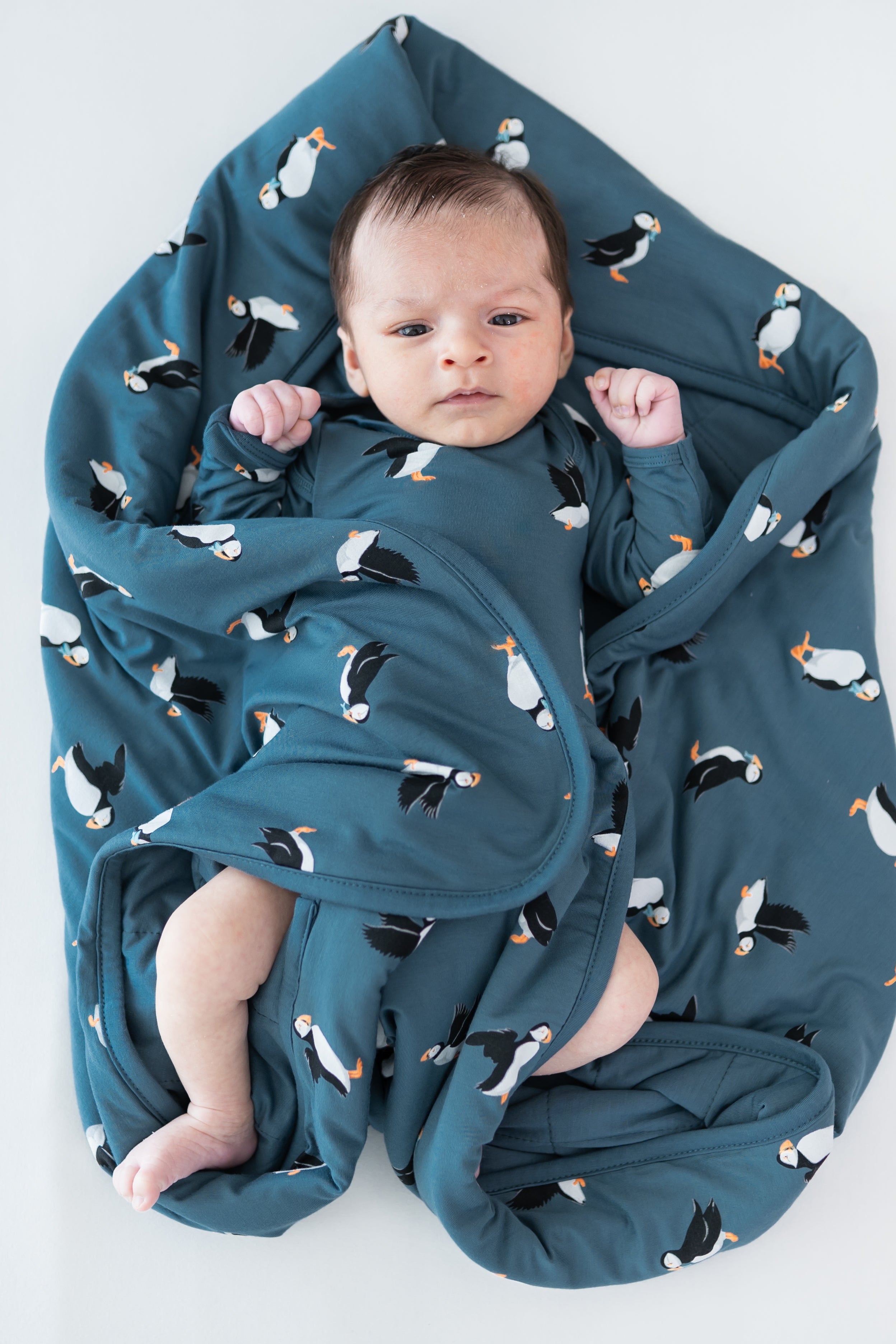 Baby laying on a Baby Blanket in Puffin wearing a matching long sleeve bodysuit