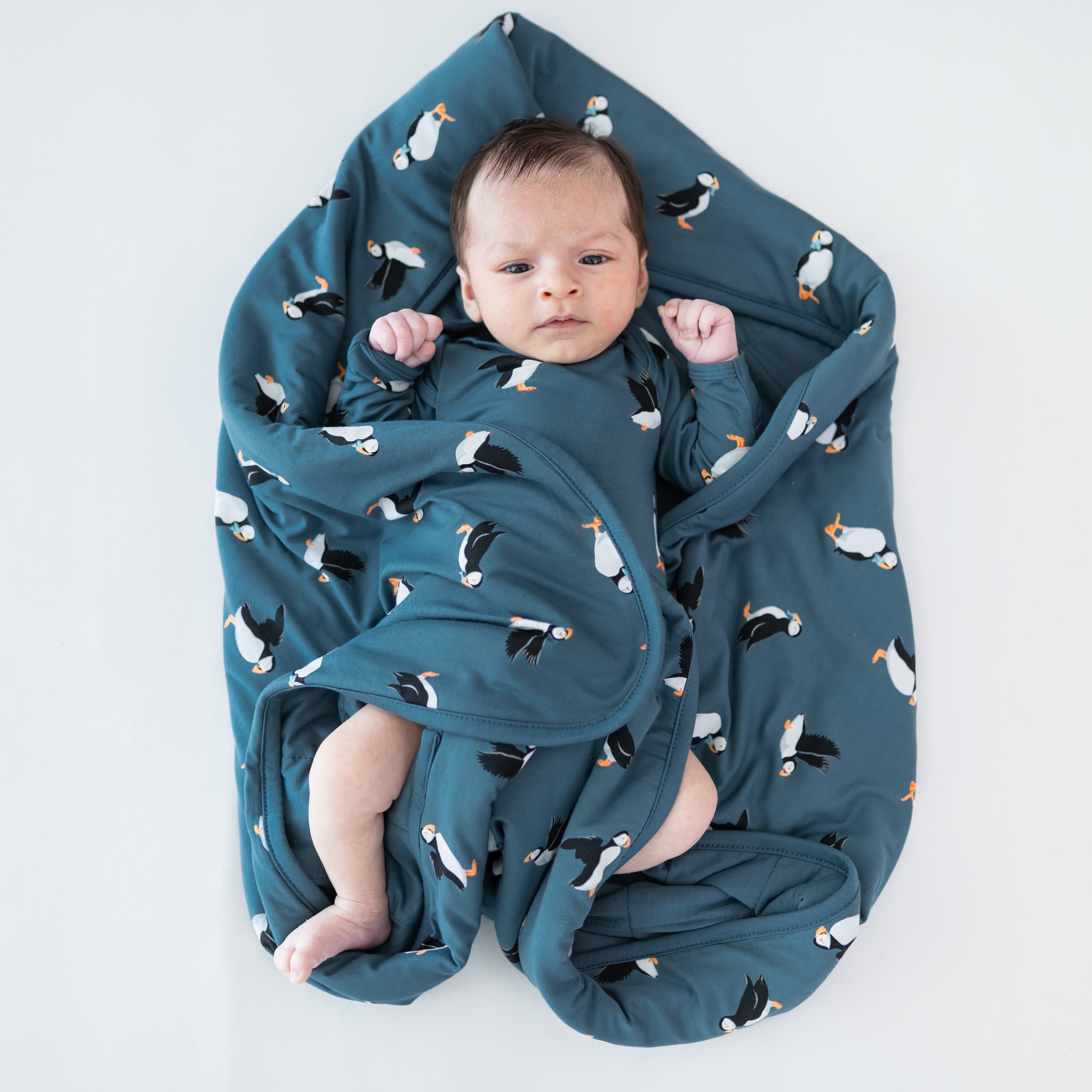 Baby laying on a Baby Blanket in Puffin wearing a matching long sleeve bodysuit