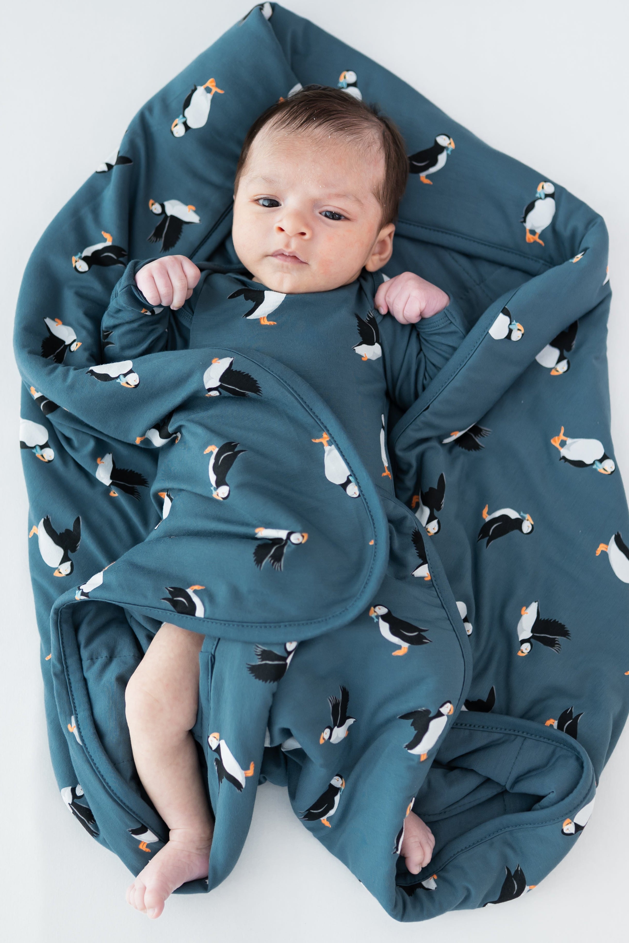 Baby laying on a Baby Blanket in Puffin wearing a matching long sleeve bodysuit