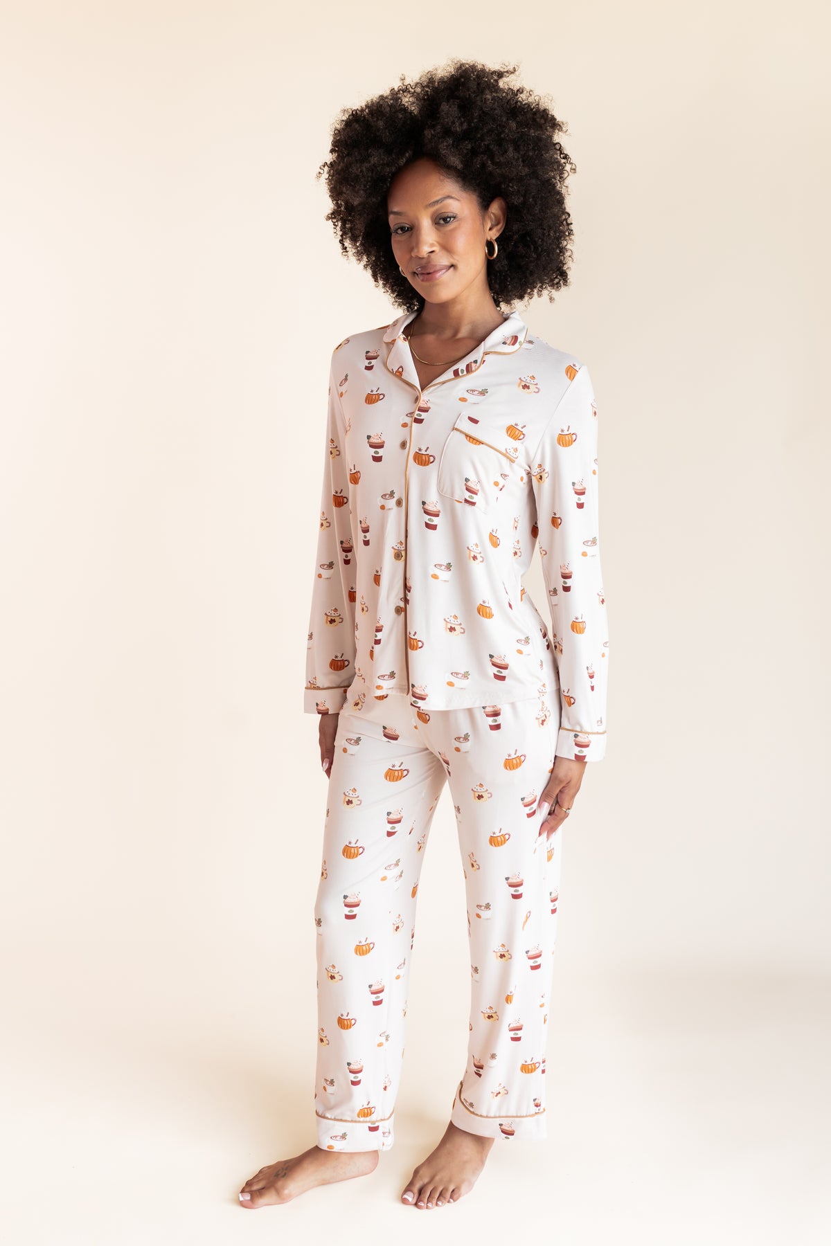Model wearing Long-Sleeved Women's Pajama Set with Pumpkin Spice Latte print on a beige background