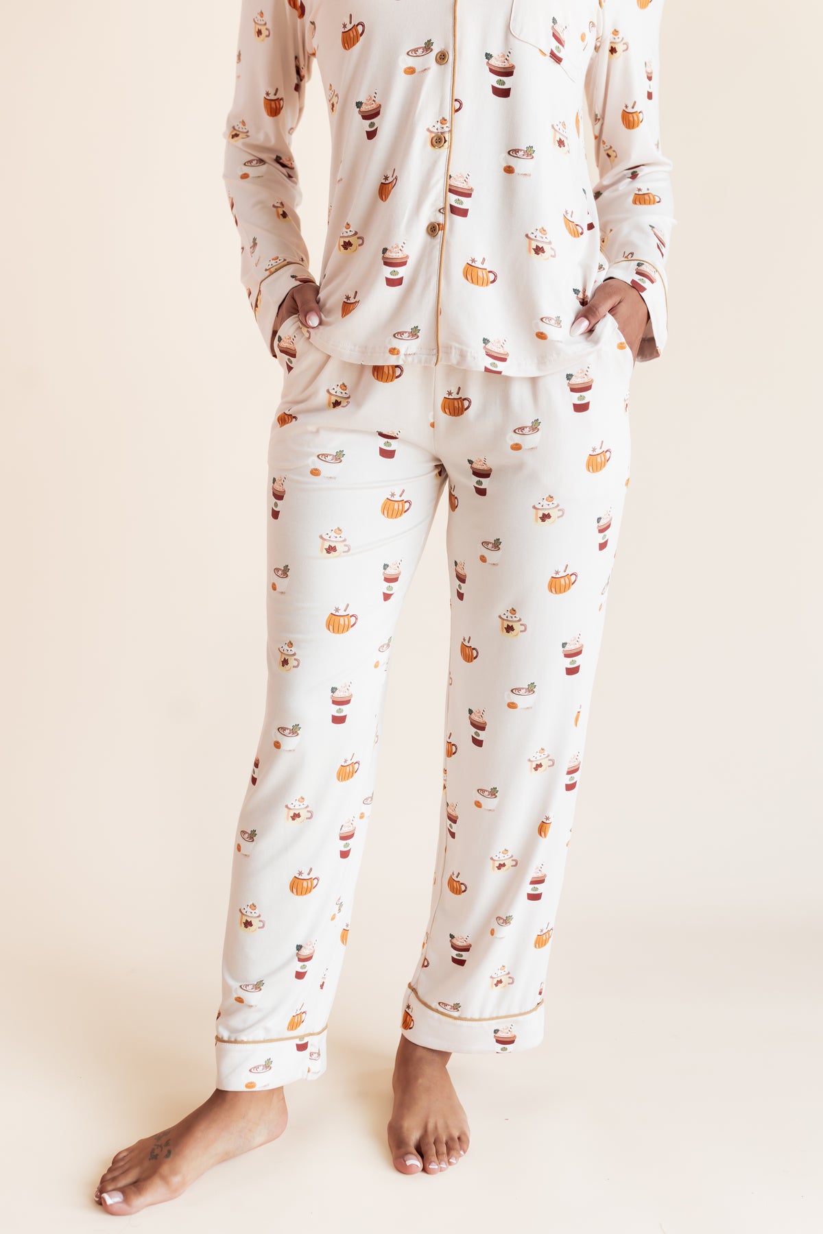 Close up of Model wearing Long-Sleeved Women's Pajama Set with Pumpkin Spice Latte print with pockets on a beige background