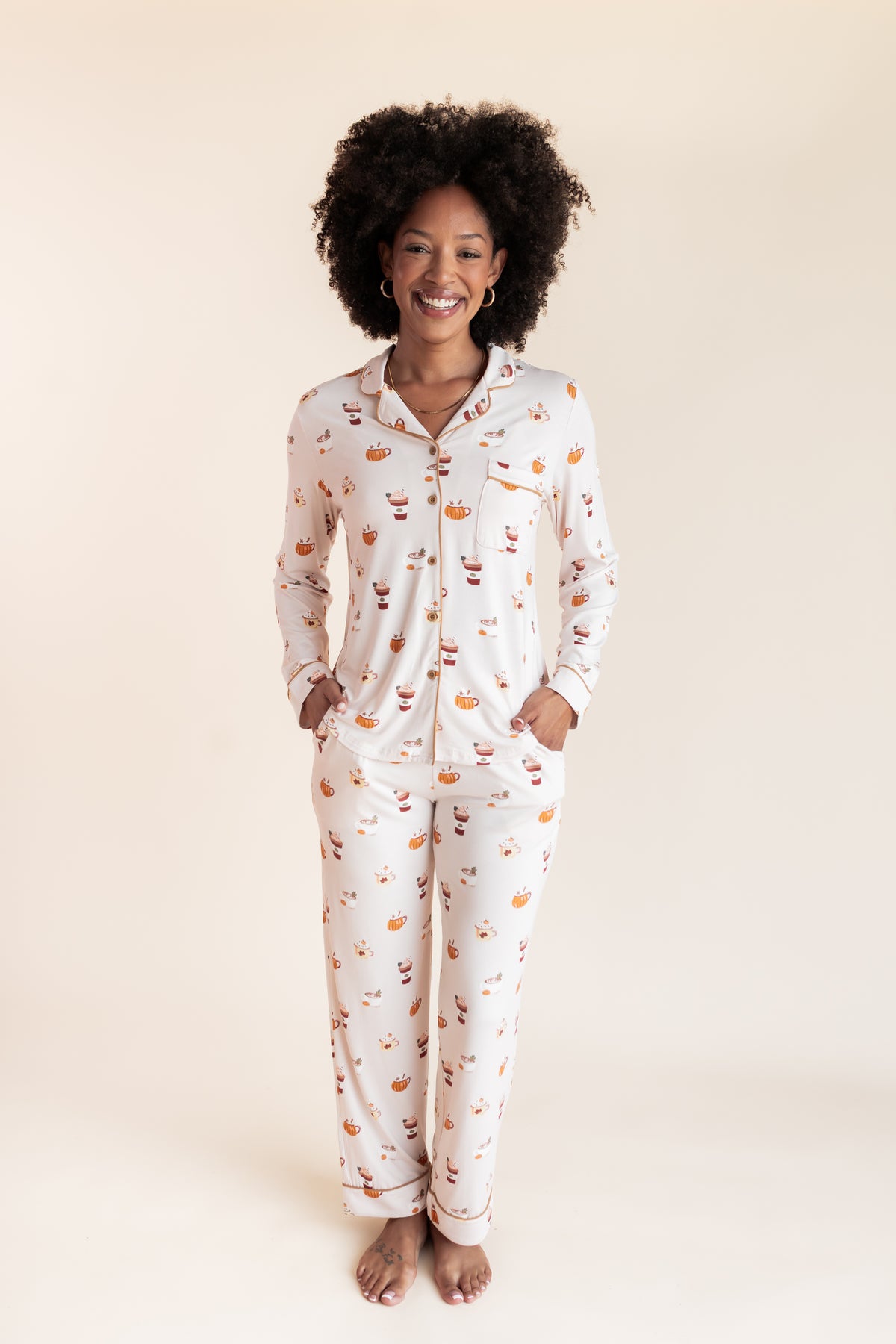 Model smiling in Long-Sleeved Women's Pajama Set with Pumpkin Spice Latte print on a beige background