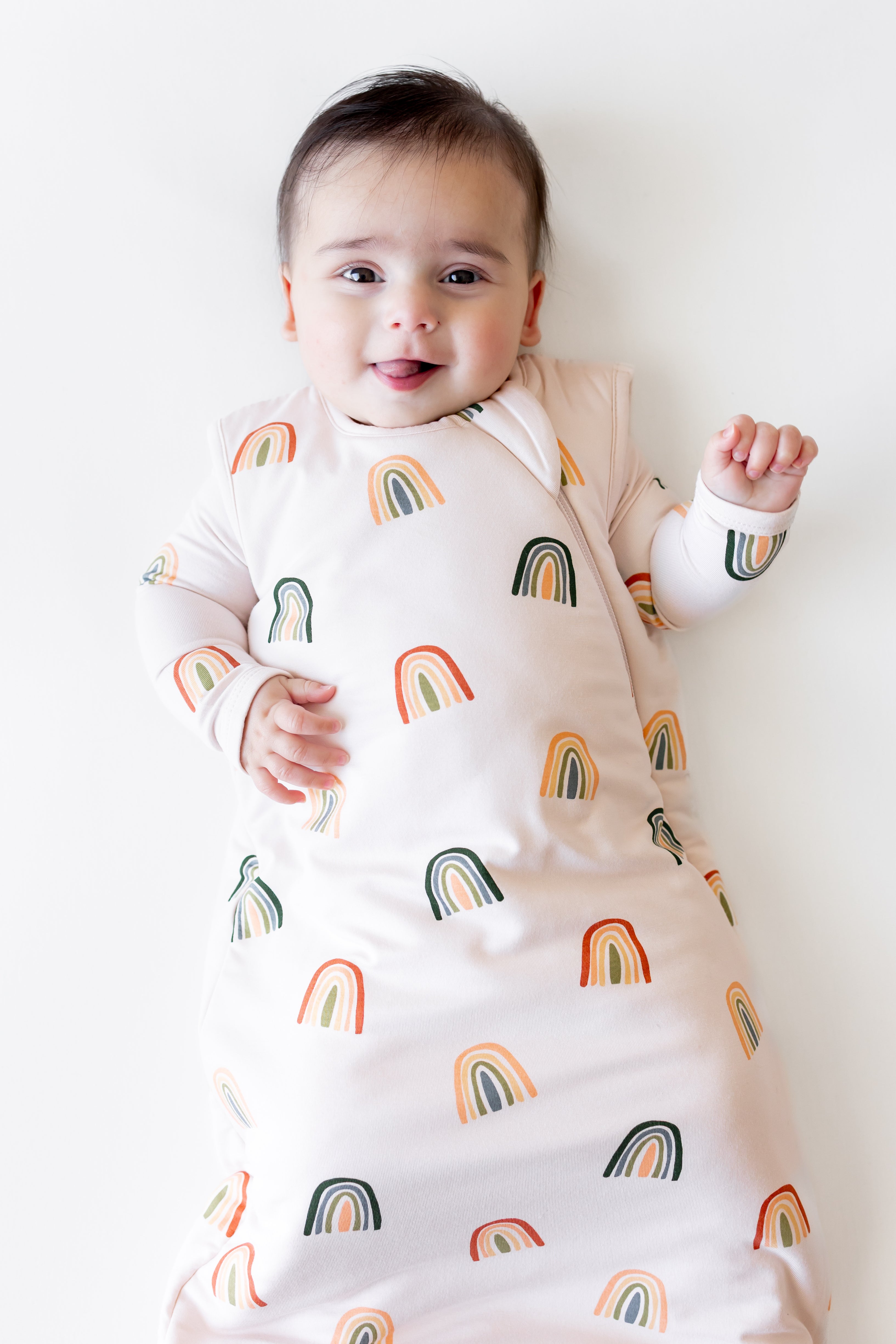 Baby smiling in Sleep Bag in Retro Rainbow 1.0 print on a white background