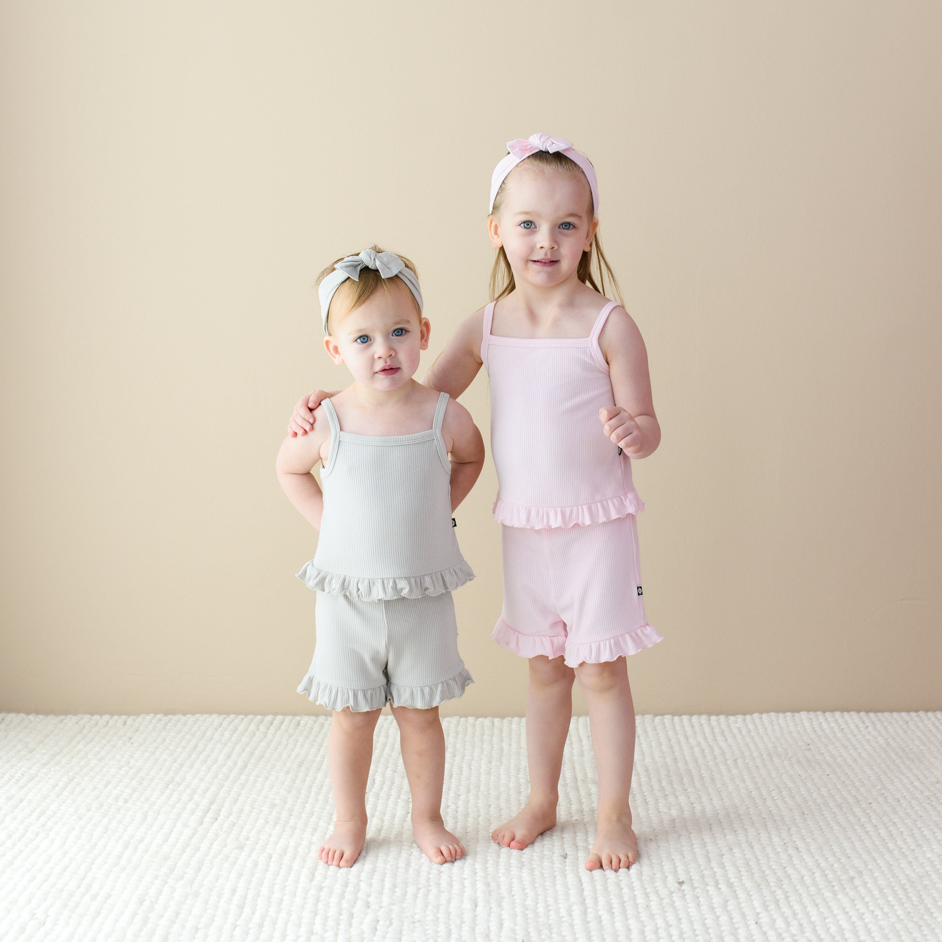 Kids wearing Ribbed Ruffle Tank and Shorts Sets in Oat and Blush with matching bows