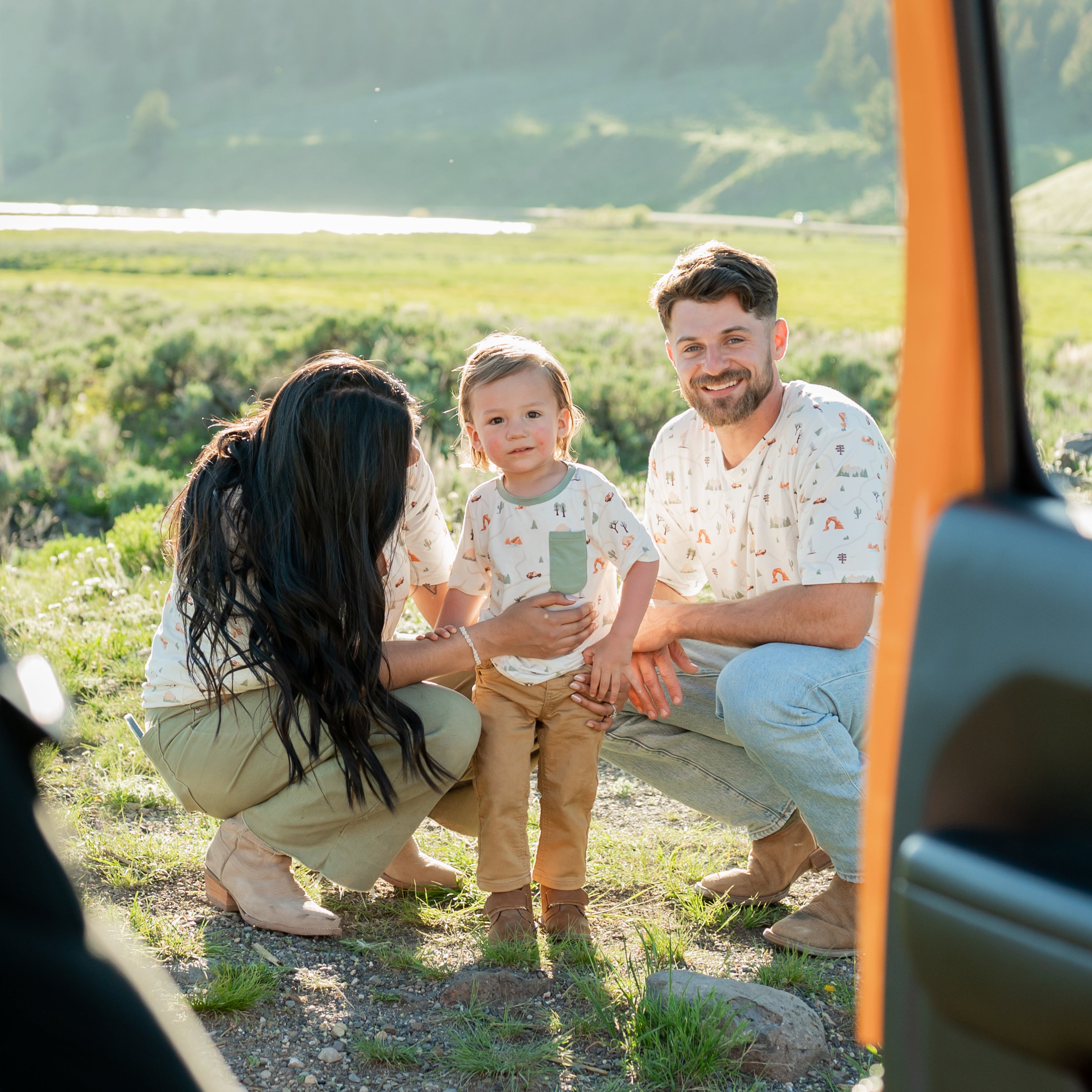 Family wearing various items in the Road Trip Collection. Pictured is the Women's Relaxed Fit V-Neck, Toddler Crew Neck Tee and Men's Crew Neck