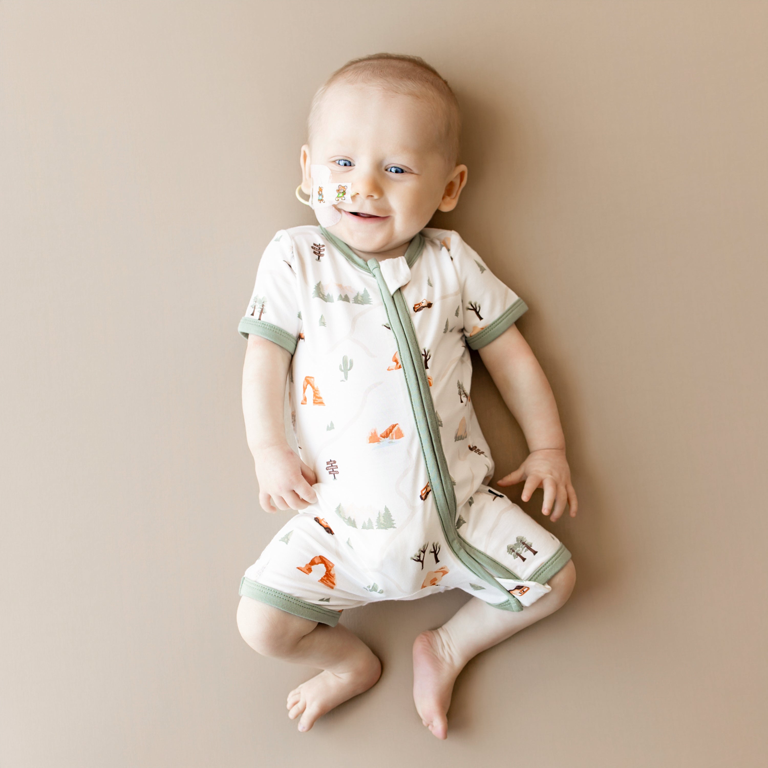 Smiling infant wearing the Zippered Shortall Romper in Road Trip