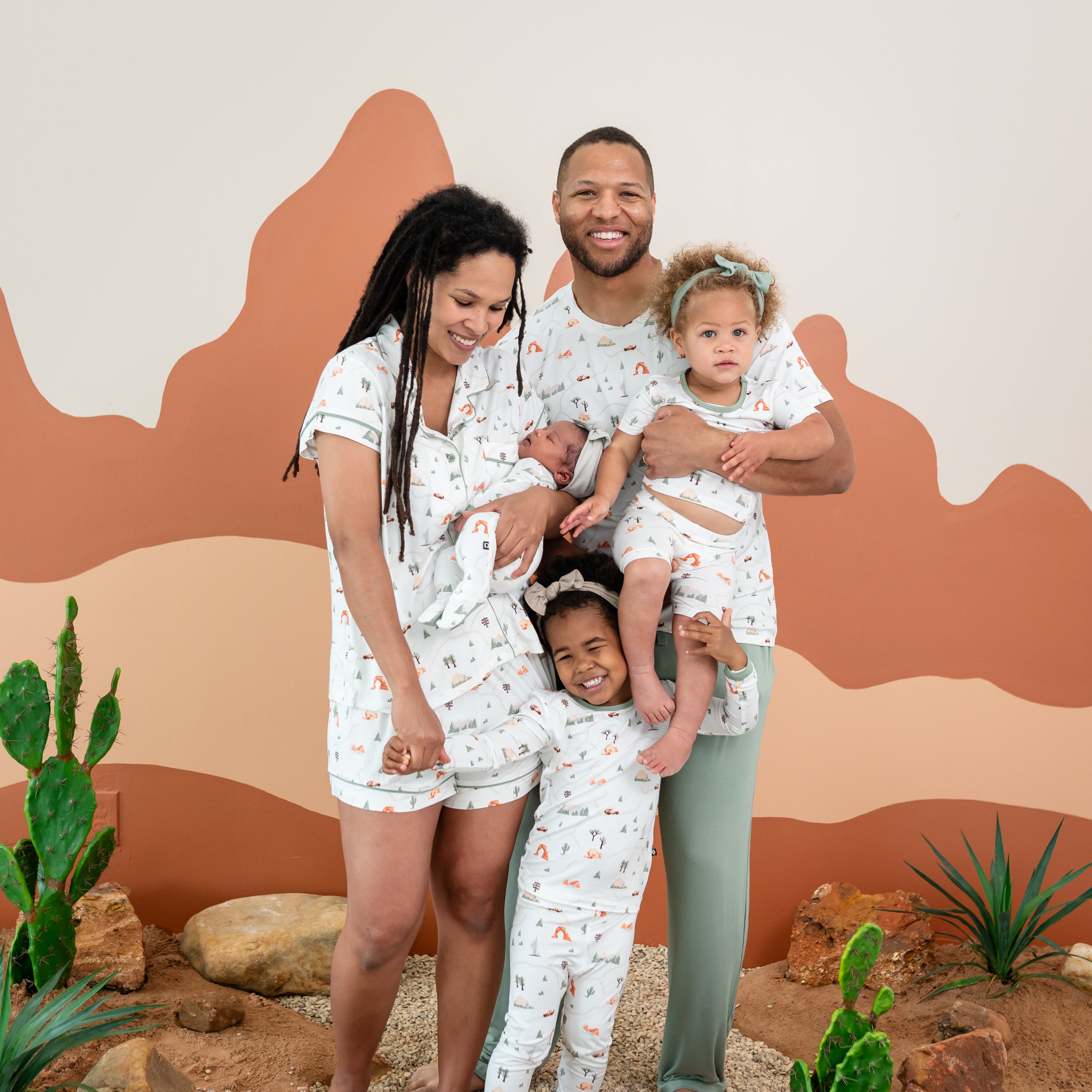 Family wearing the Road Trip collection. Pictured items are the Women's Short Sleeve Pajama Set, Men's Crew neck, Short and Long sleeve pajama set and zippered footie
