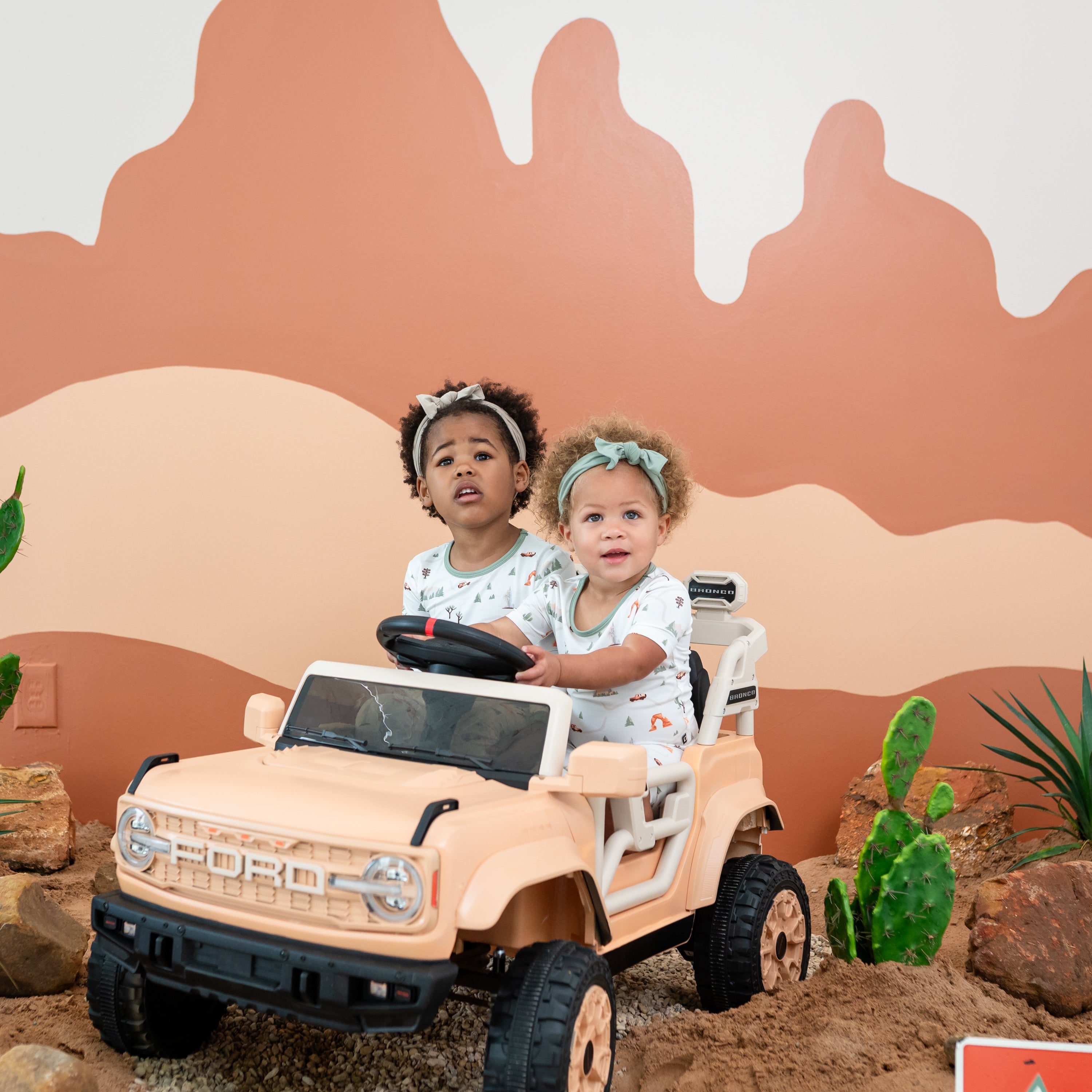 Two sisters sitting in a battery powered ford vehicle wearing the Short Sleeve and Long Sleeve Pajamas in Road Trip