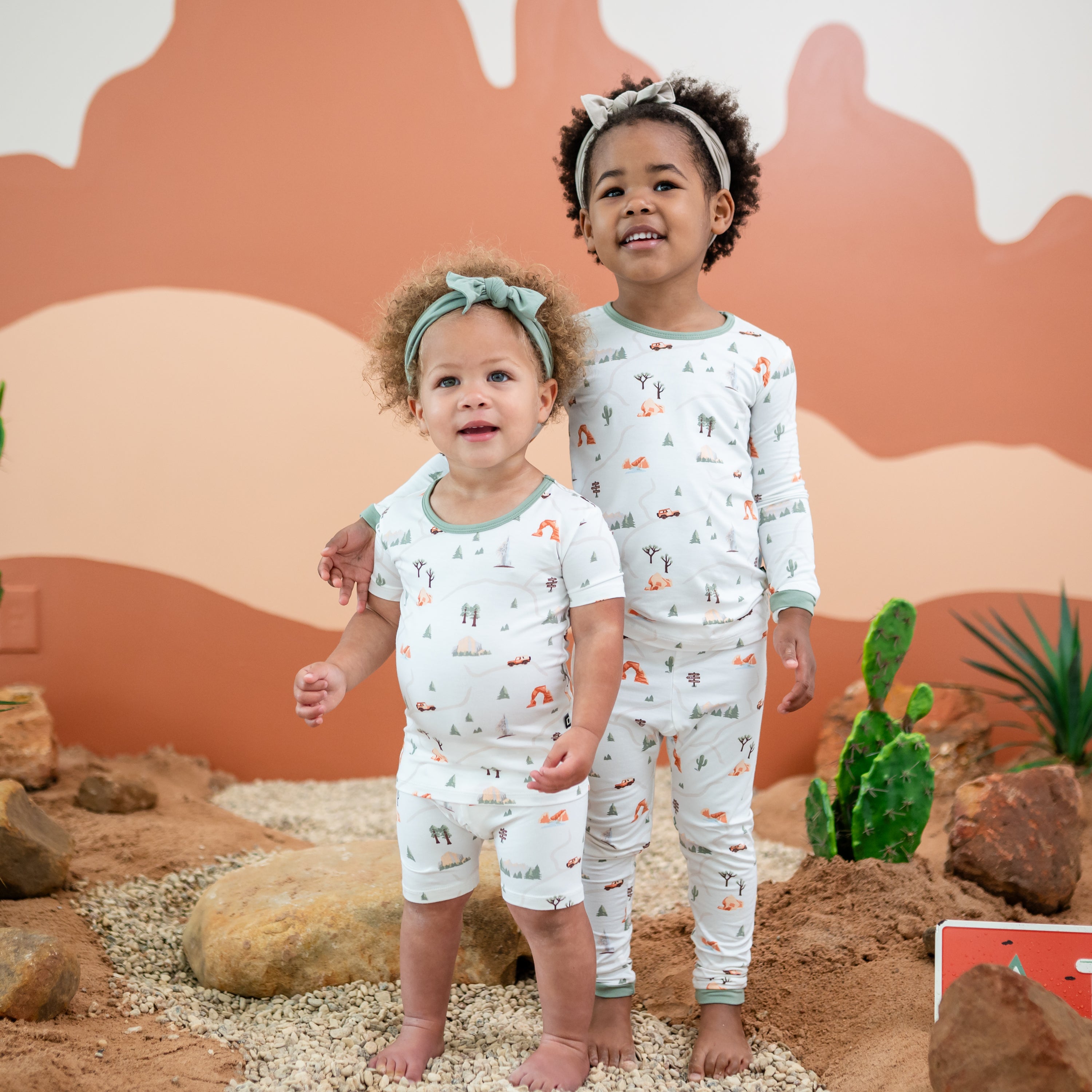 Two sisters standing side by side wearing the Short Sleeve and Long Sleeve Pajamas in Road Trip