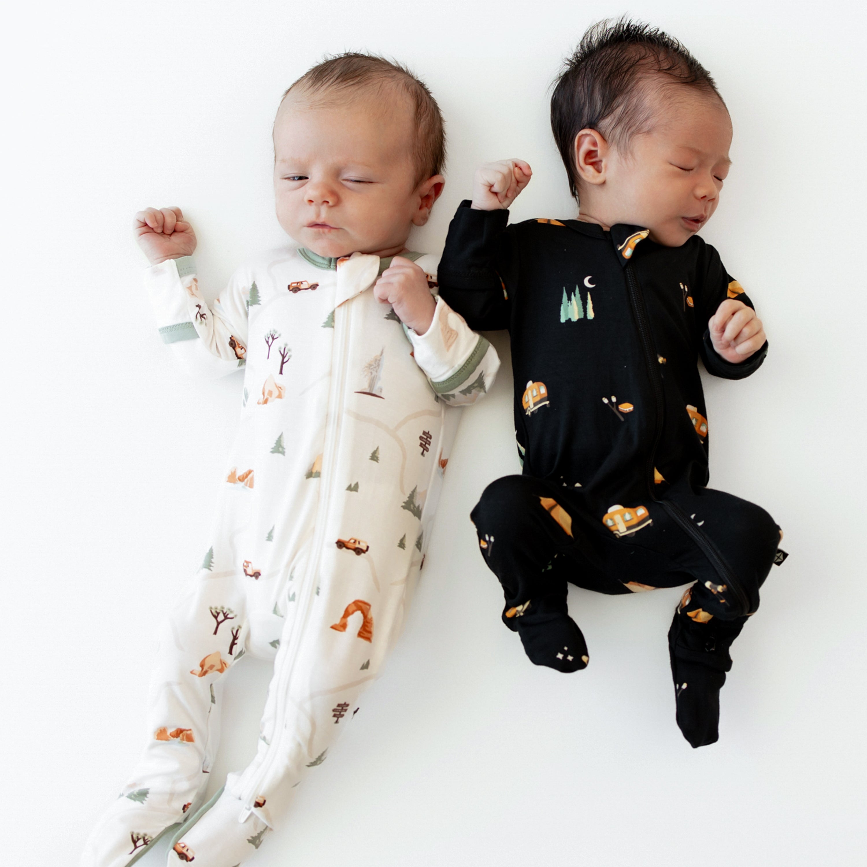 Two newborn babies wearing Road Trip and Under the Stars Zippered Footie pajamas