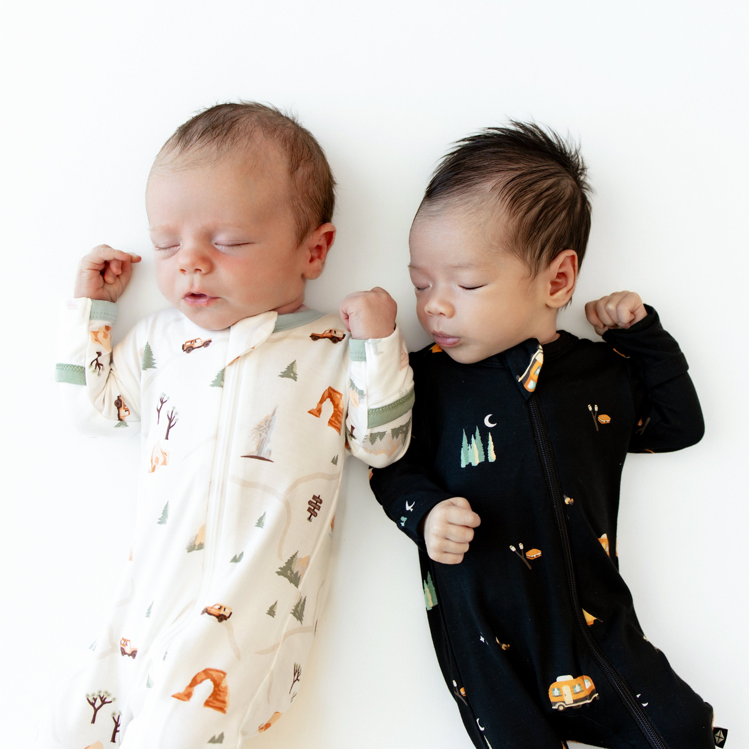 Two sleeping newborns wearing National Parks Road Trip and Under the Stars Zippered Footies