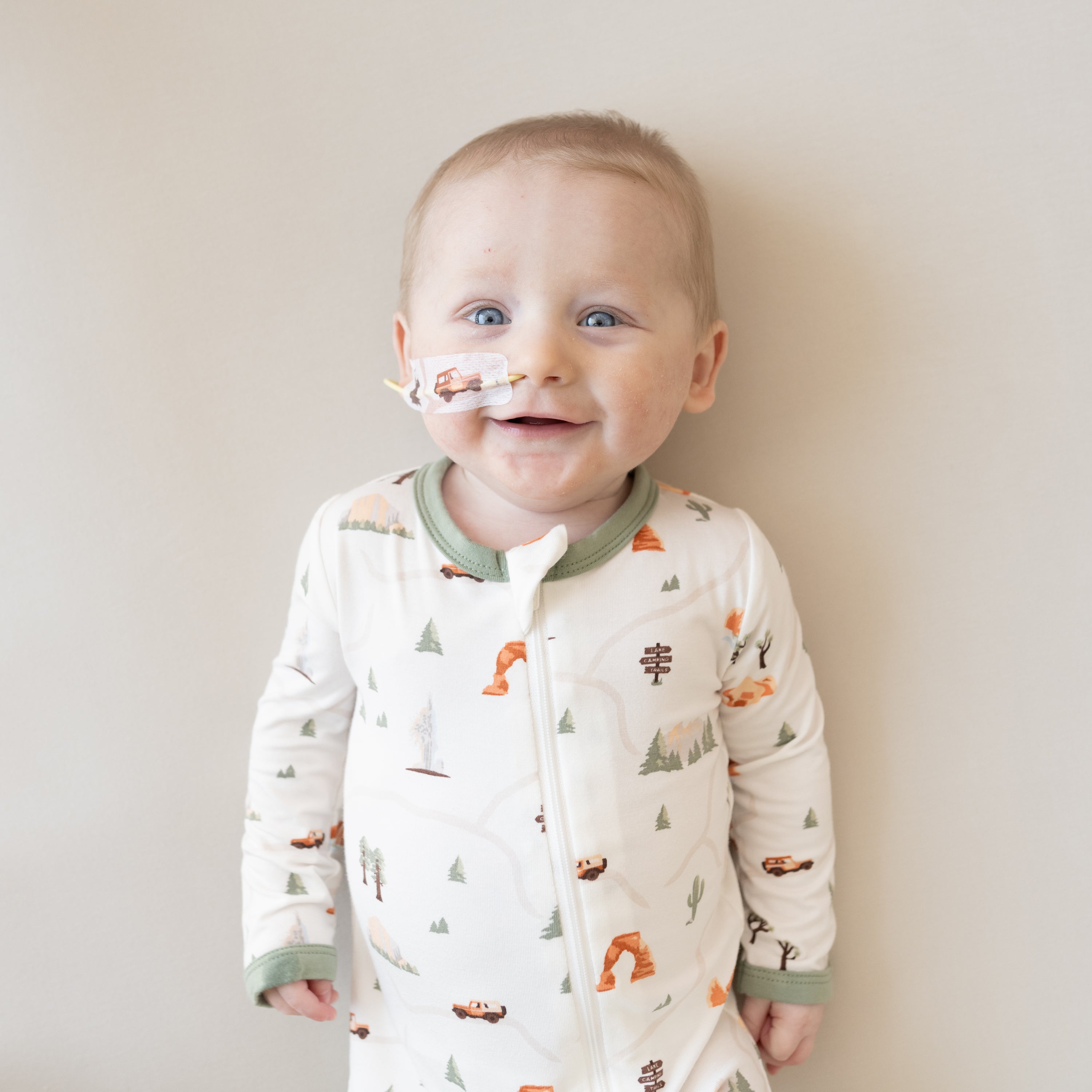 Smiling infant wearing the Zippered Romper in Road Trip