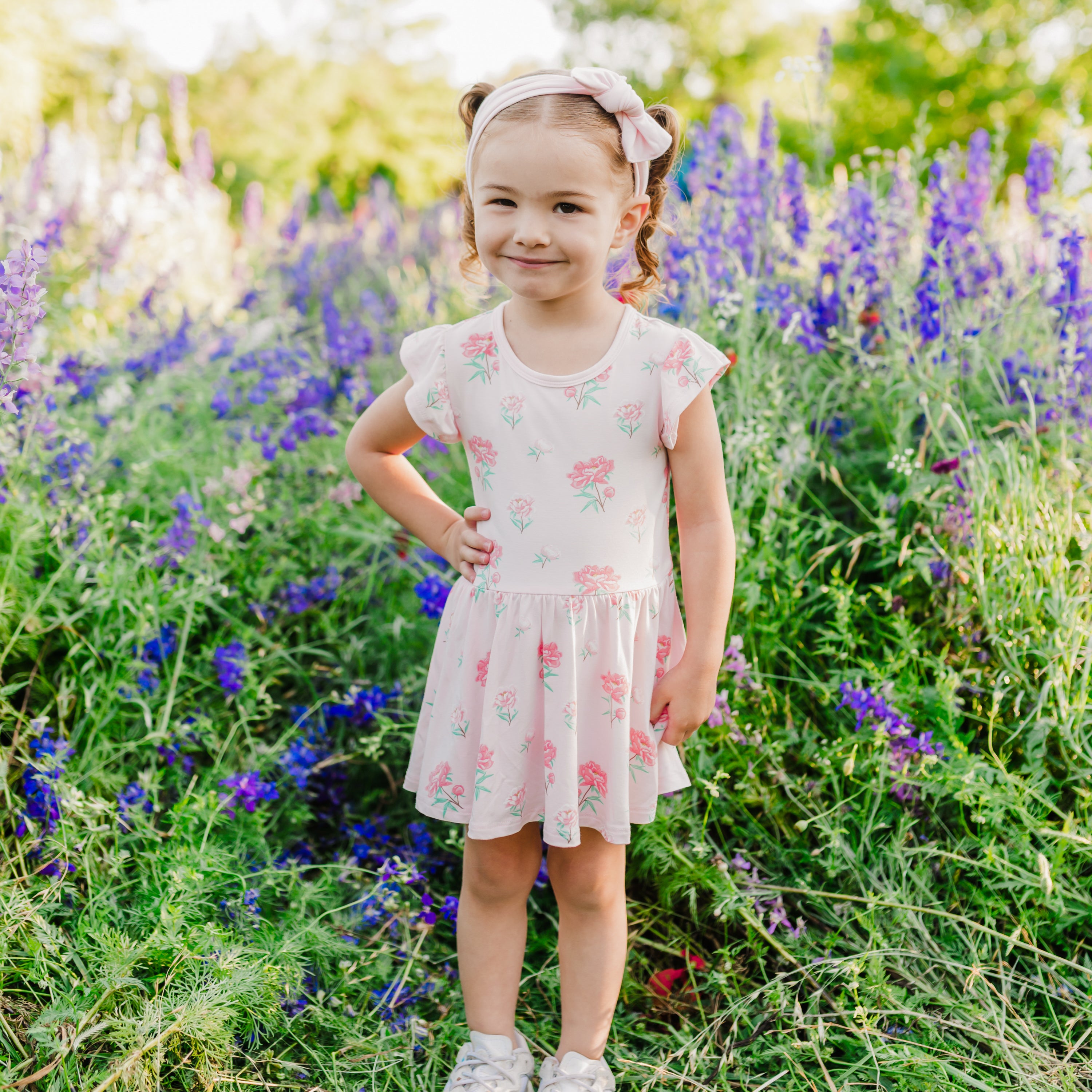 Toddler modeling Twirl Bodysuit Dress in Sakura Peony with wildflower background