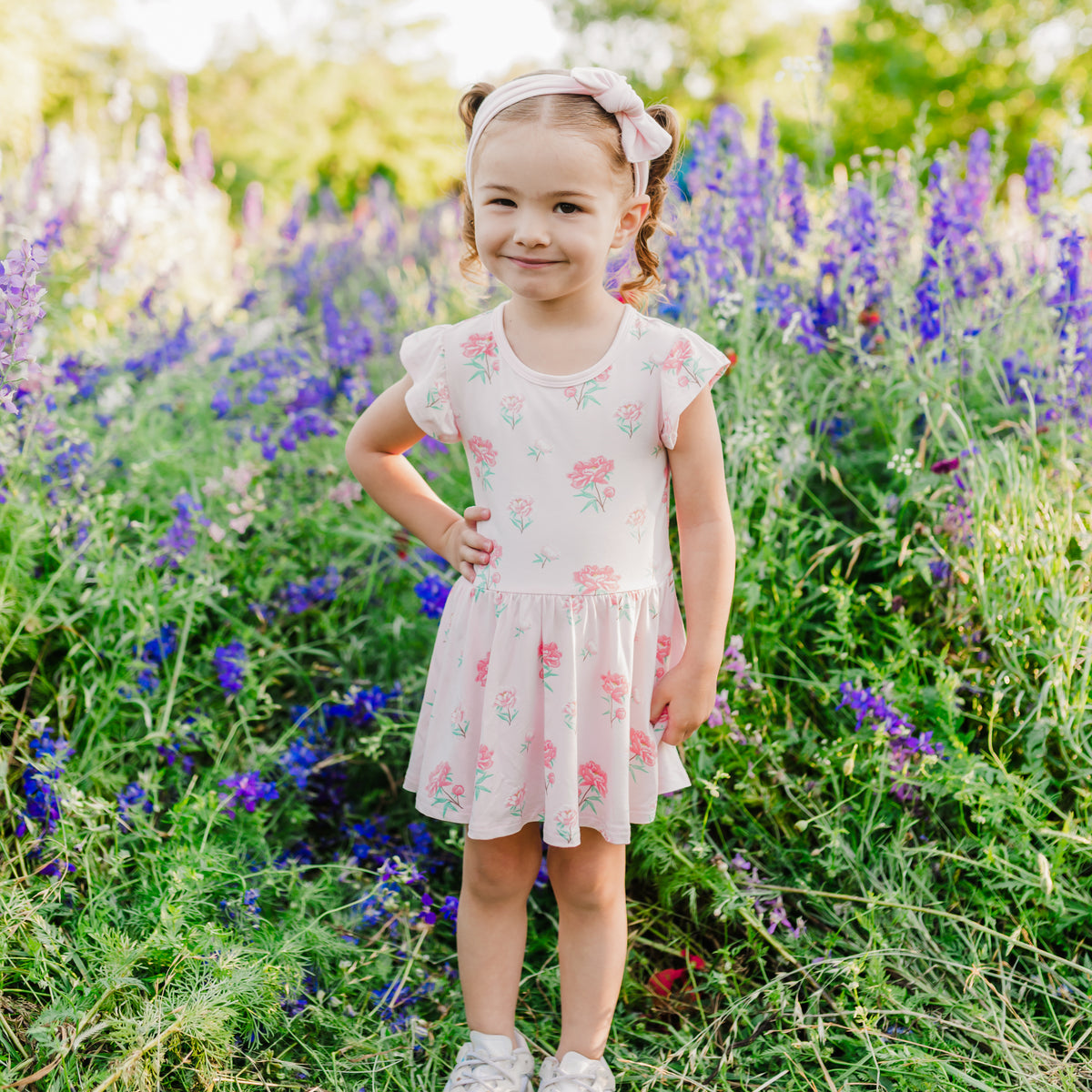 Toddler modeling Twirl Bodysuit Dress in Sakura Peony with wildflower background