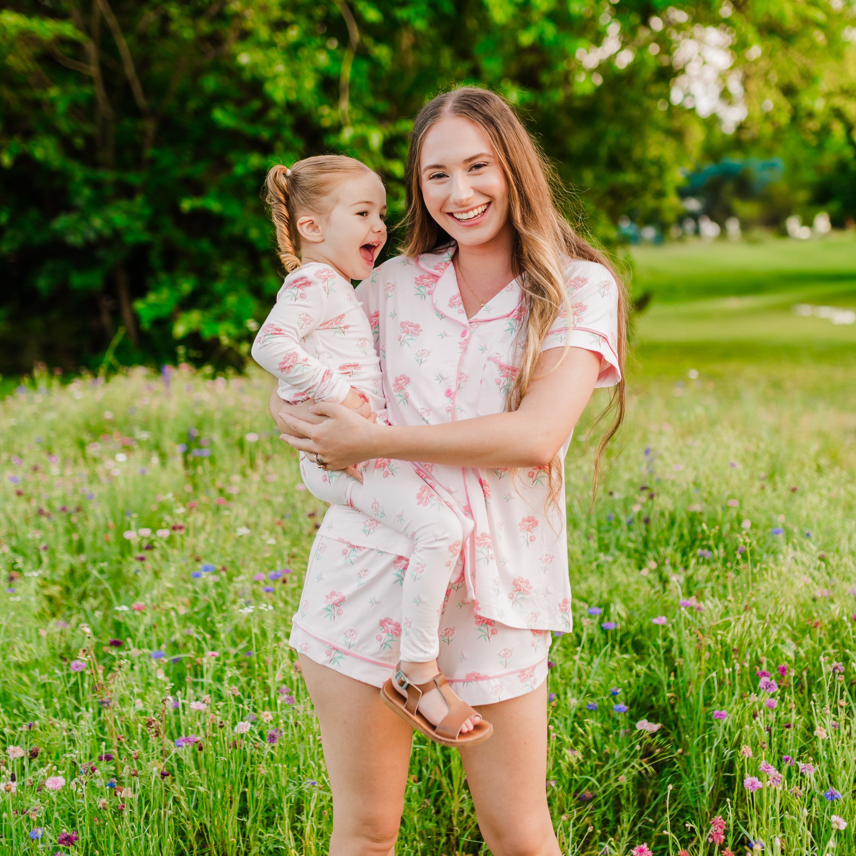 Woman wearing Women's Short Sleeve Pajama Set in Sakura Peony holding toddler in matching pajamas