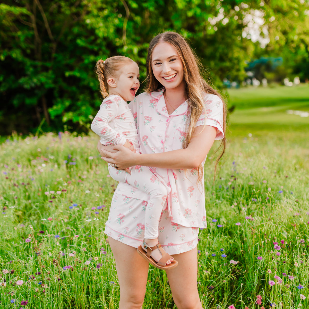 Woman wearing Women's Short Sleeve Pajama Set in Sakura Peony holding toddler in matching pajamas