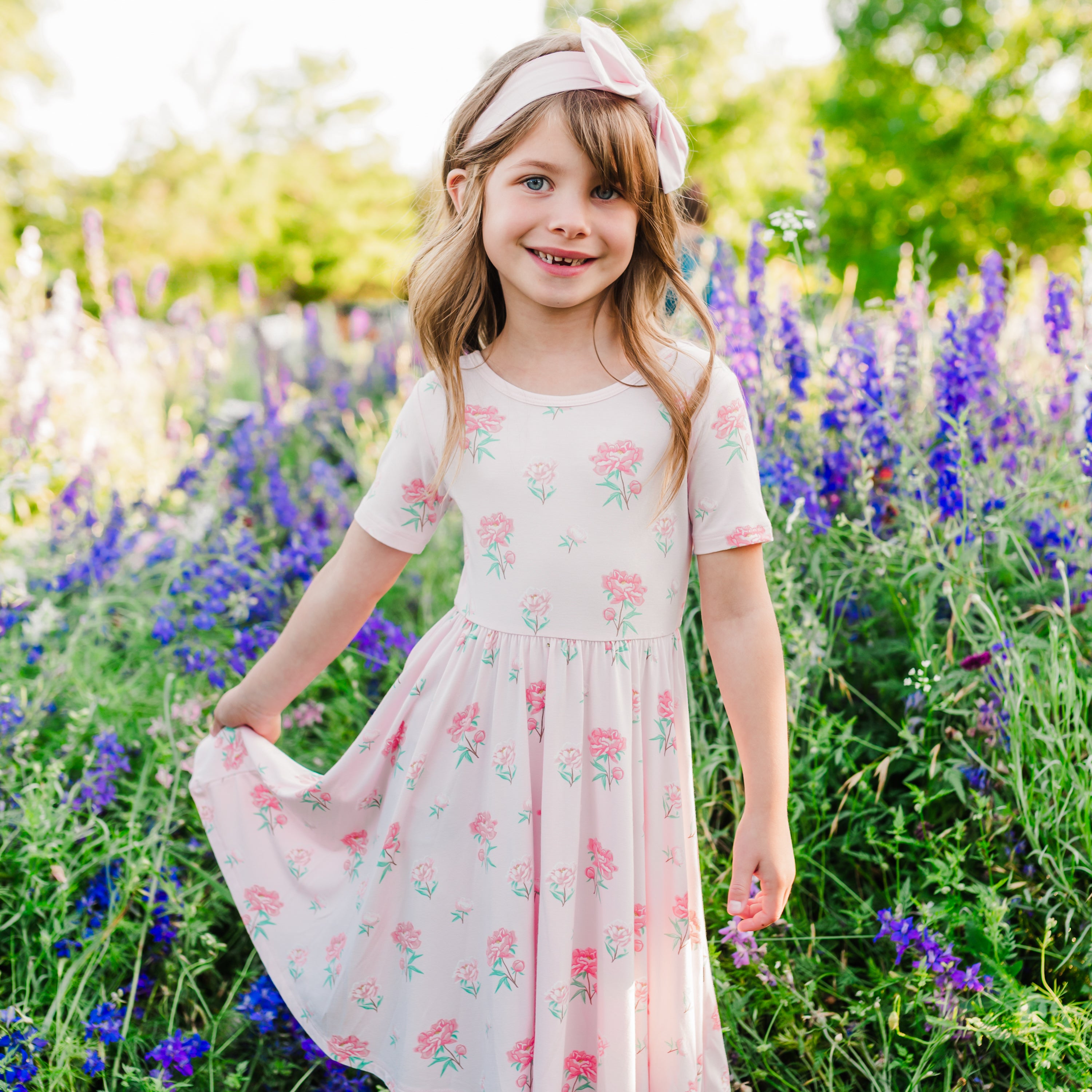 Child modeling Twirl Dress in Sakura Peony with a wildflower field in background
