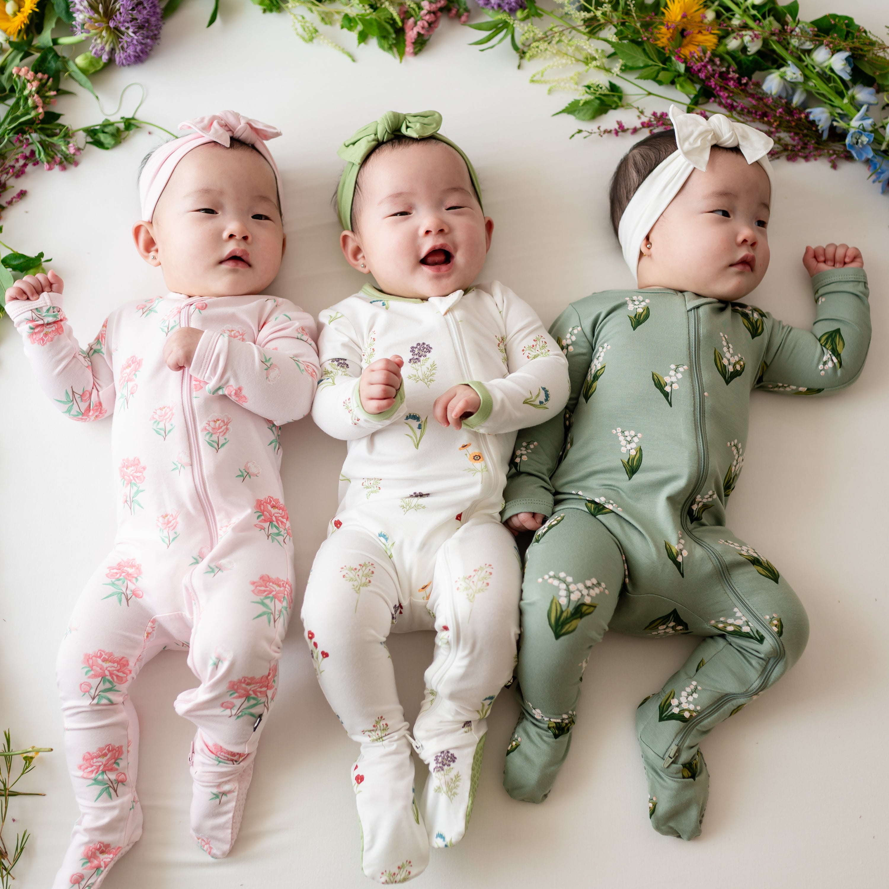 Group photo of 3 babies in Sakura Peony, Wildflower and Thyme Lily Zippered Footies