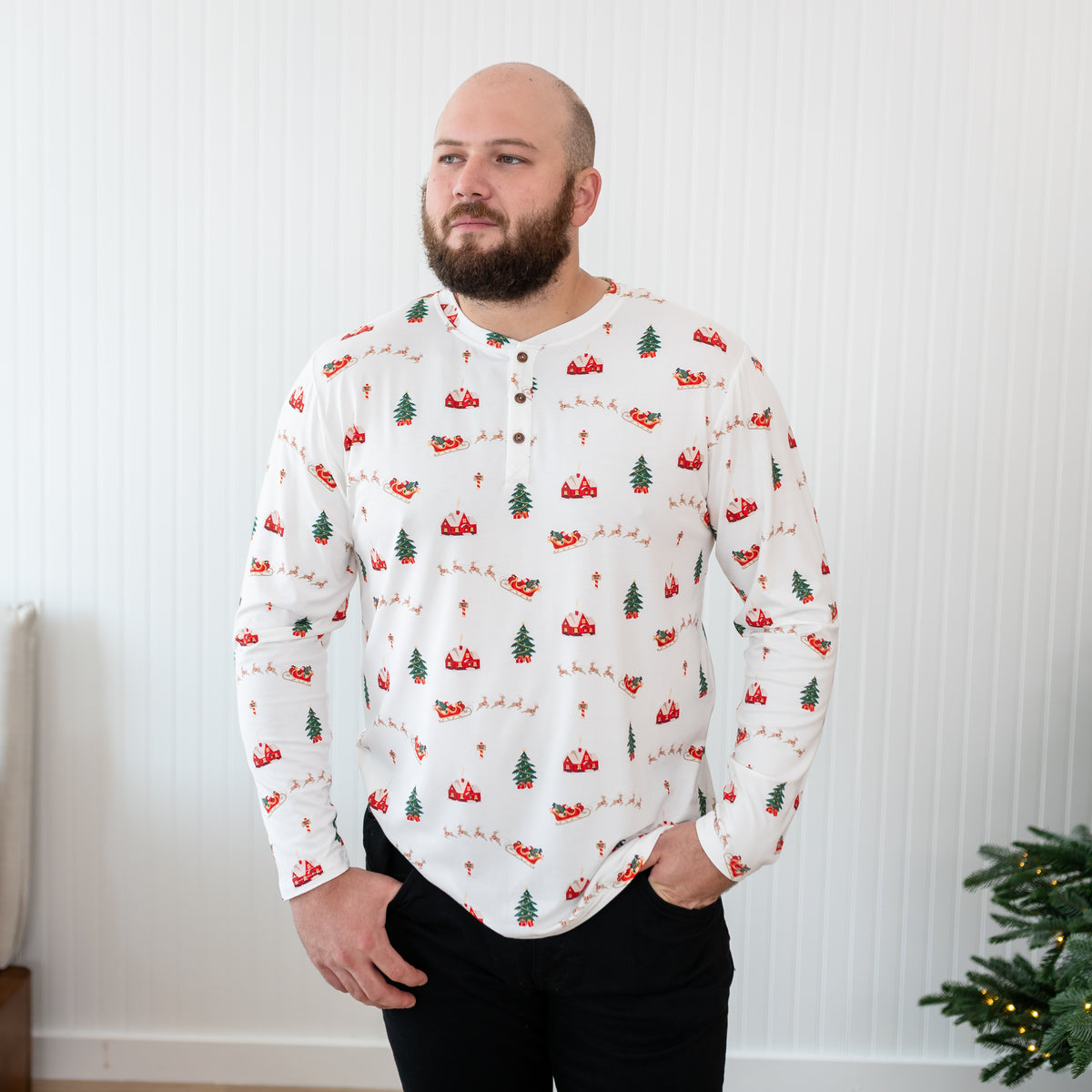 Male model wearing the Men's Long Sleeve Henley Top in Santa Sleigh with his hands in his black jeans pocket