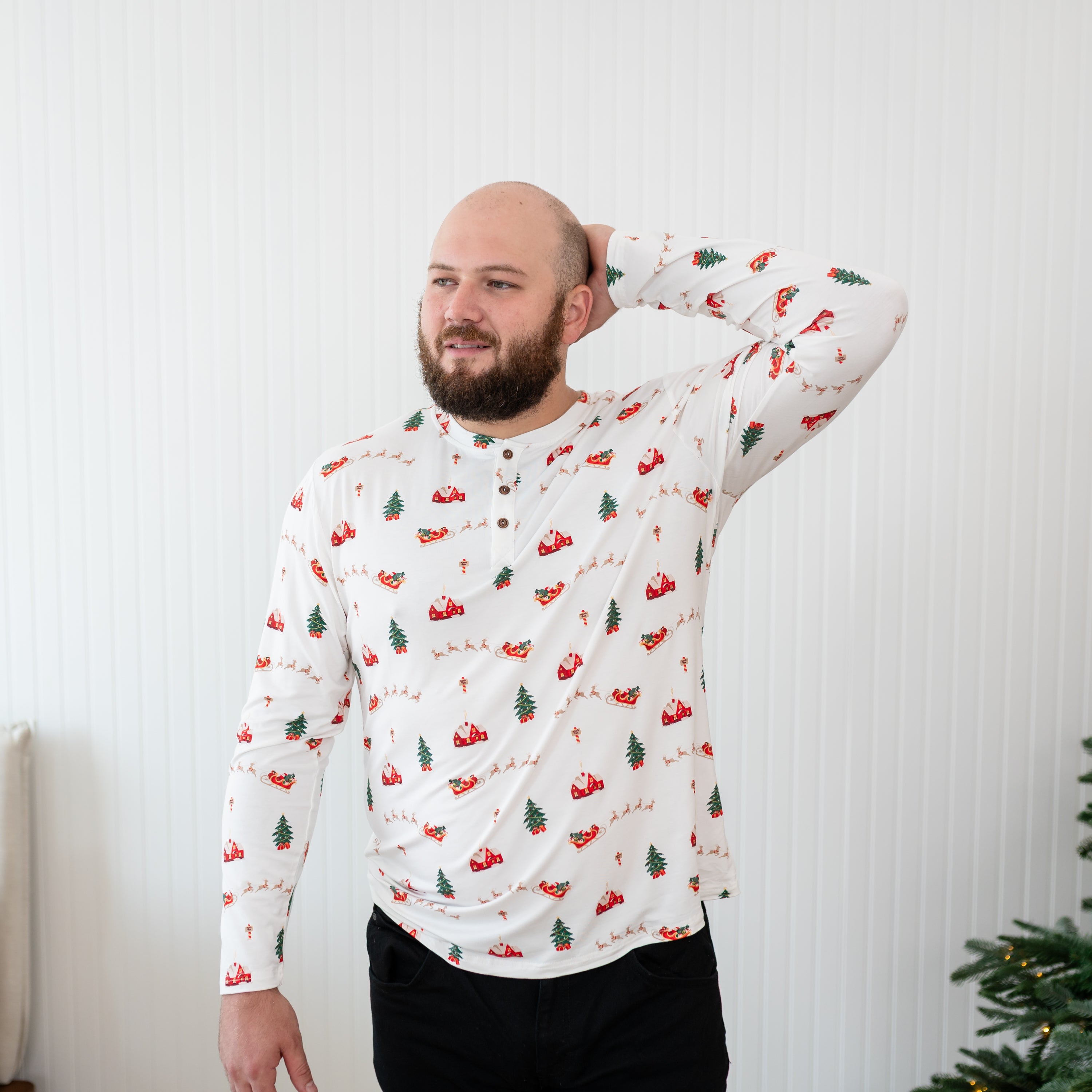 Male model standing with one arm behind his head wearing the Men's Long Sleeve Henley Top in Santa Sleigh
