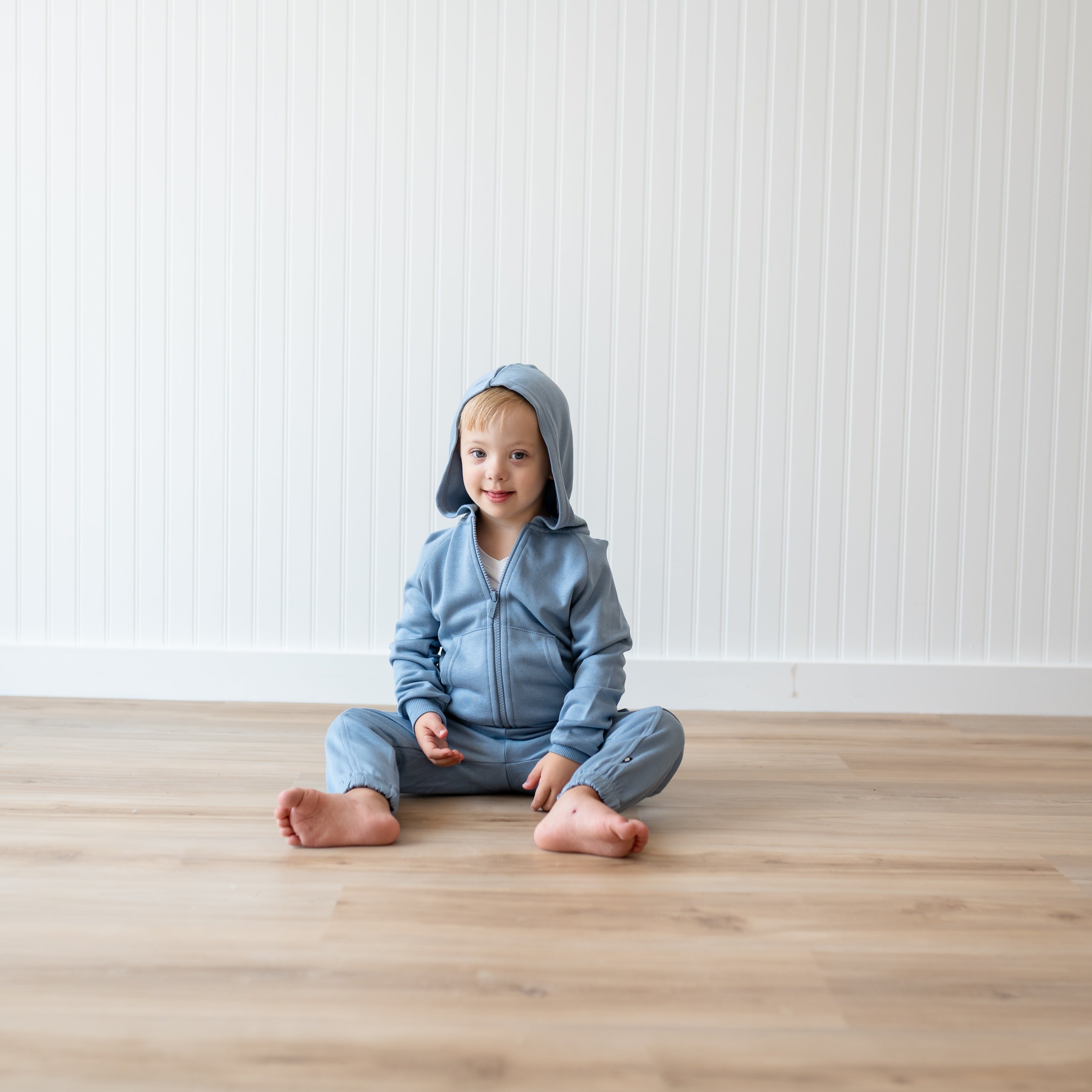 Young boy sitting on the floor wearing the Fleece Zip Up Hoodie in Slate and matching fleece cargo pant
