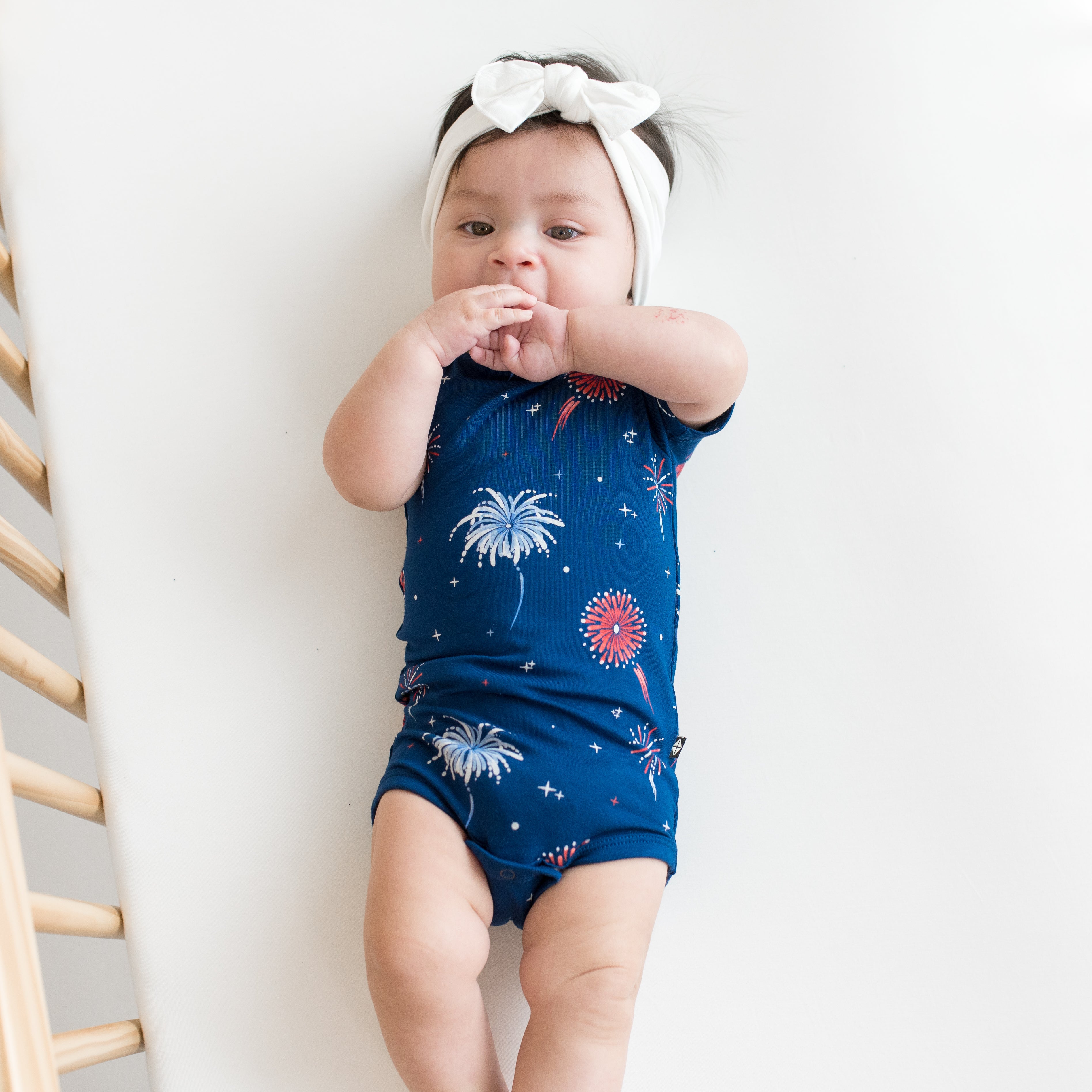 Baby in crib modeling Bodysuit in Celebration and Cloud Bow