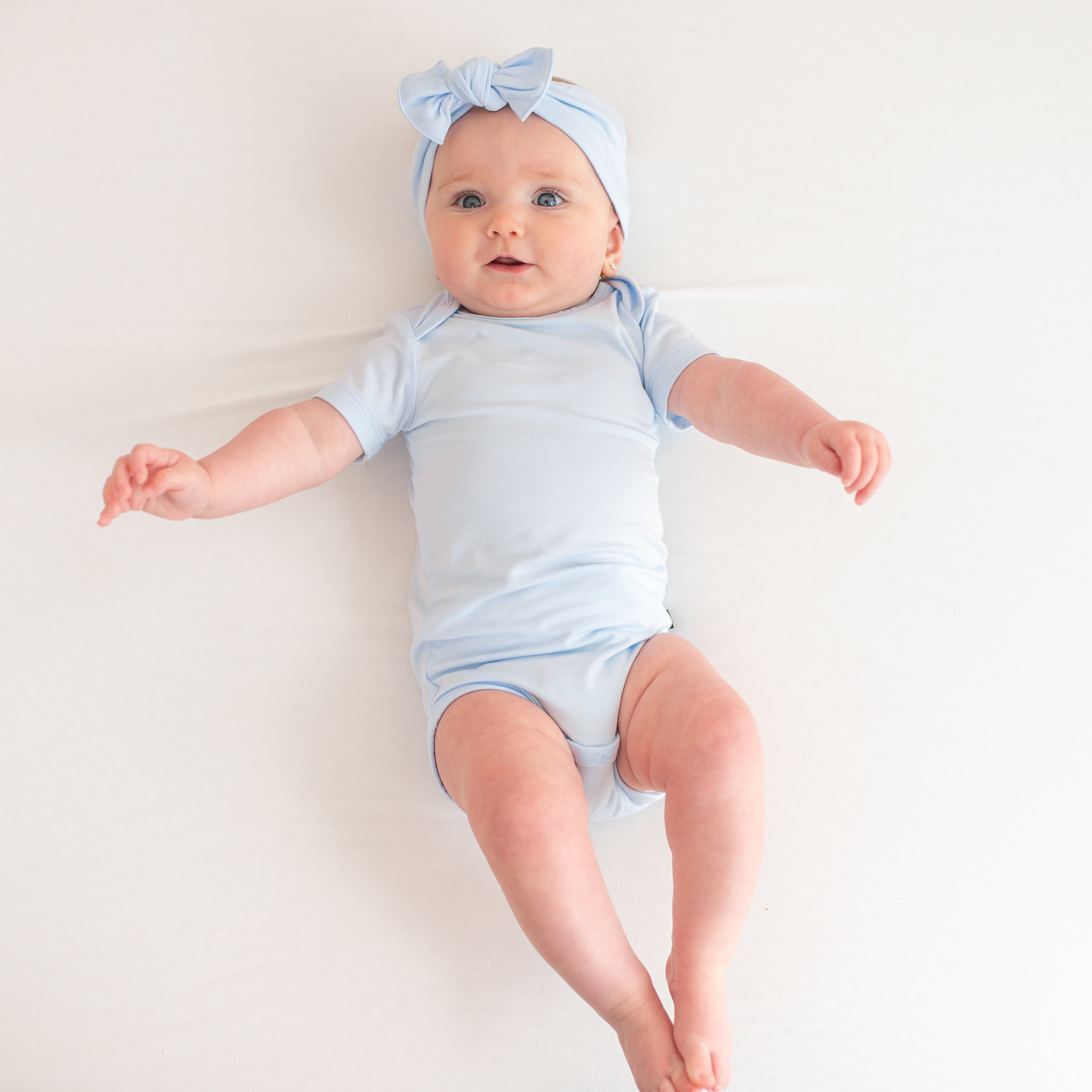 Baby model wearing the Bodysuit in Mist with matching knotted bow