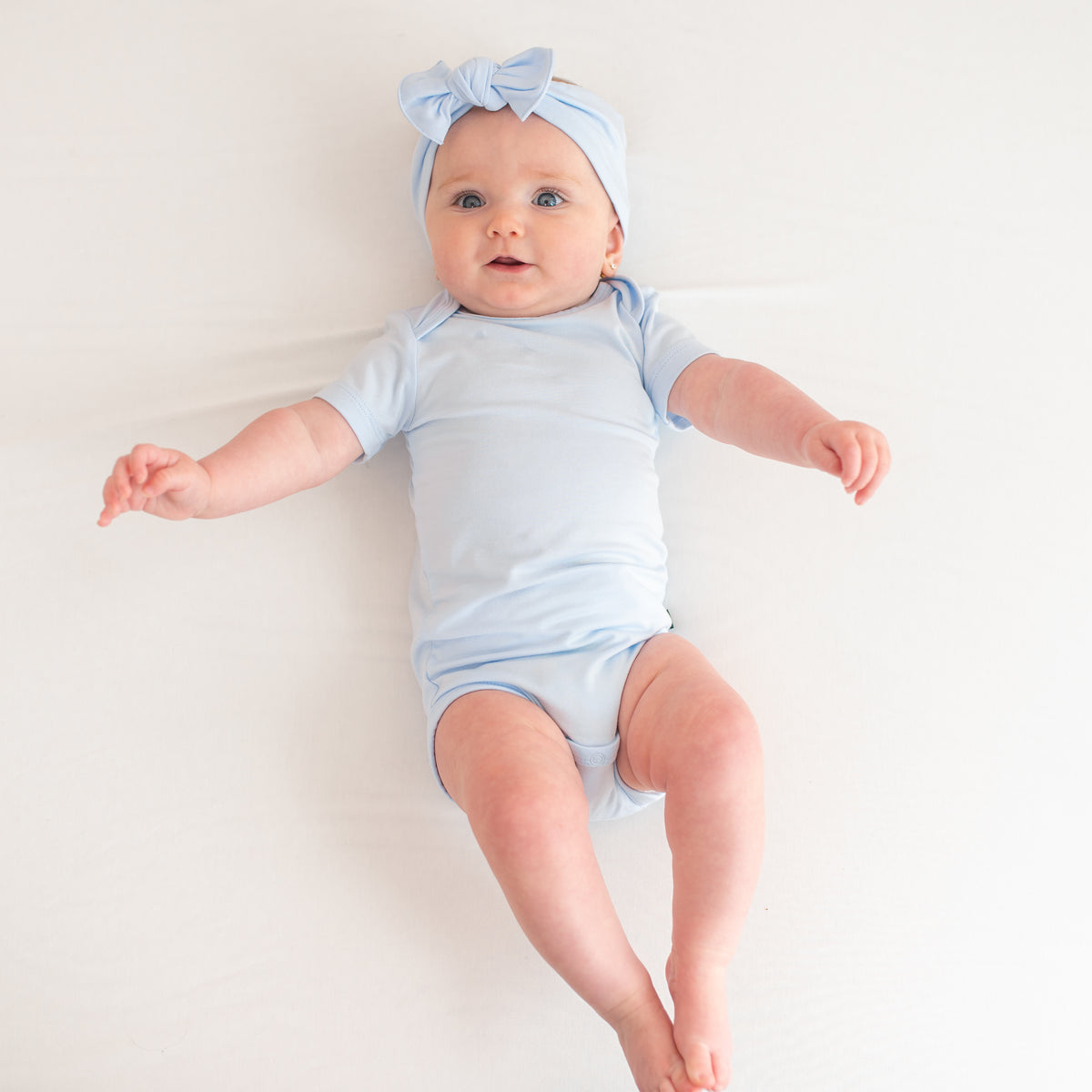Baby model wearing the Bodysuit in Mist with matching knotted bow