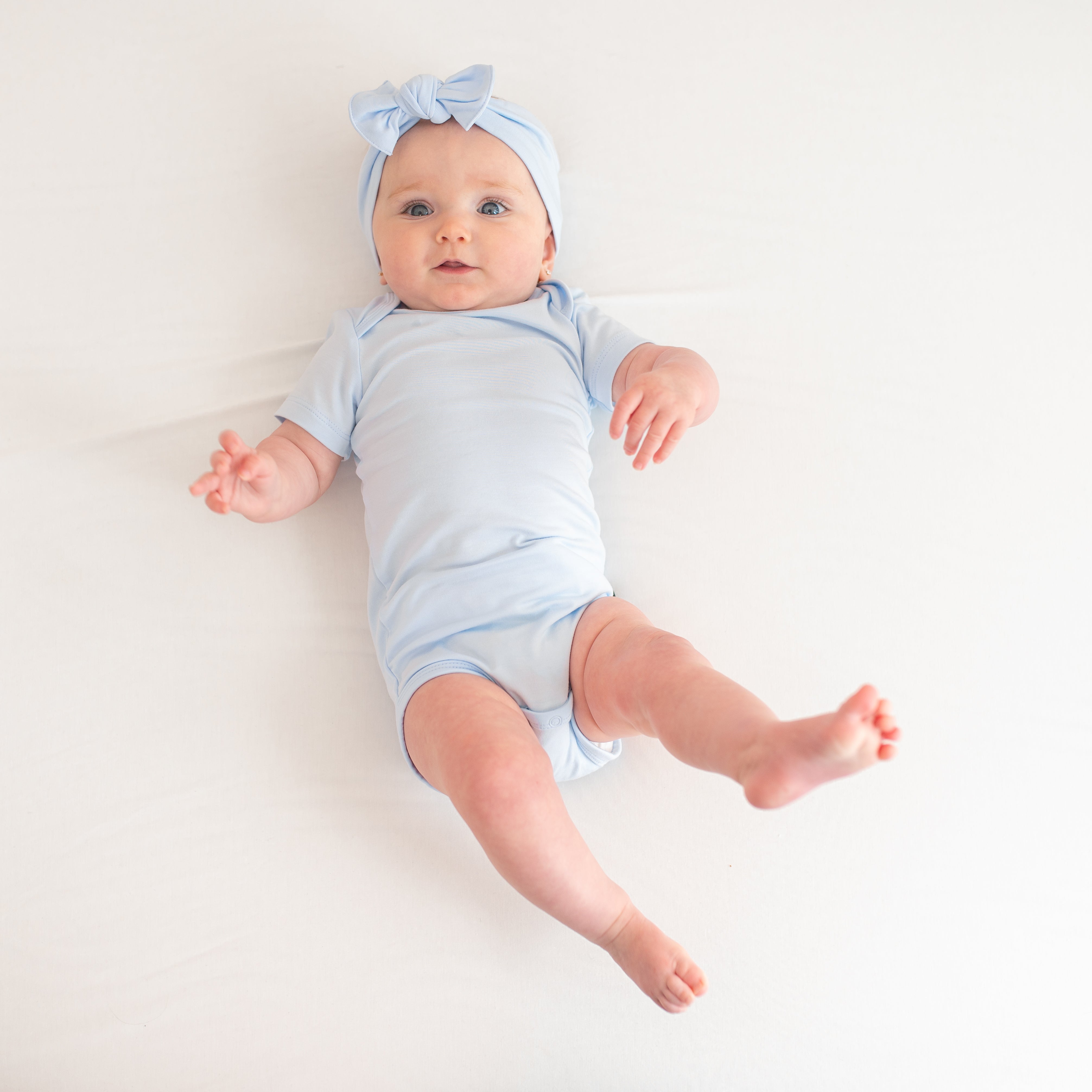 Infant model wearing the Bodysuit in Mist with a matching knotted bow