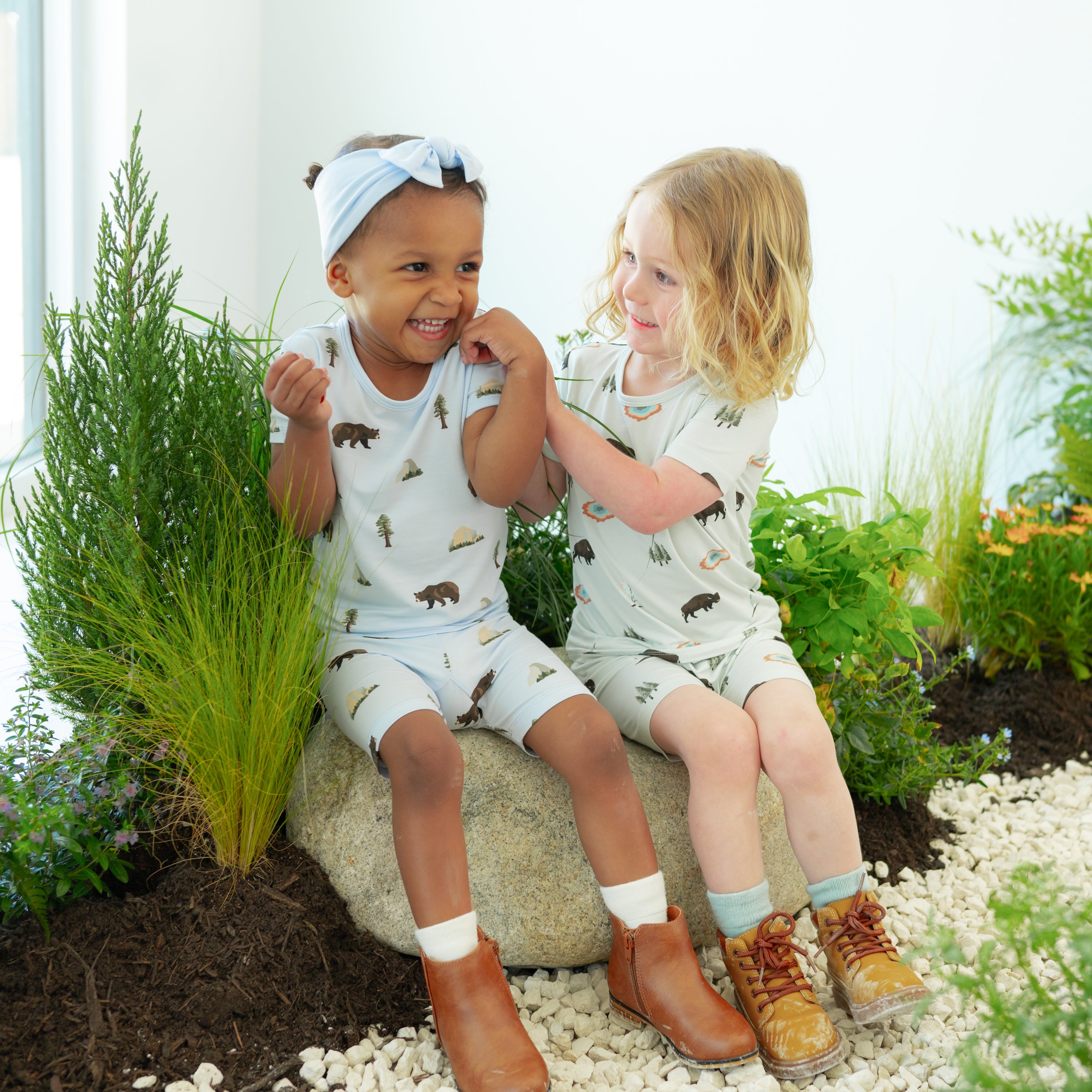 2 toddlers wearing Short Sleeve Pajamas in Yellowstone and Yosemite sitting together on a nature trail