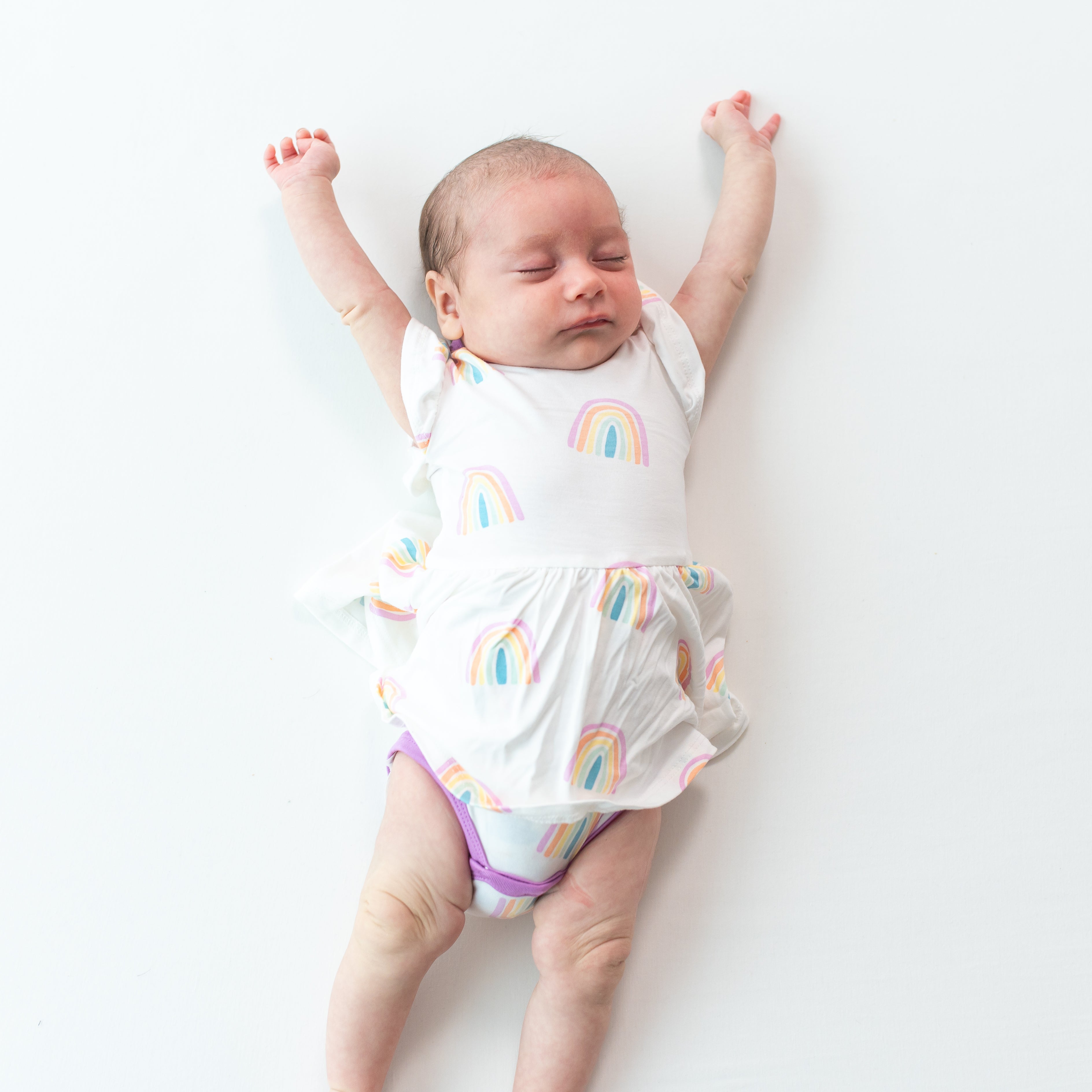Baby stretching and wearing Twirl Bodysuit Dress in Poi Rainbow