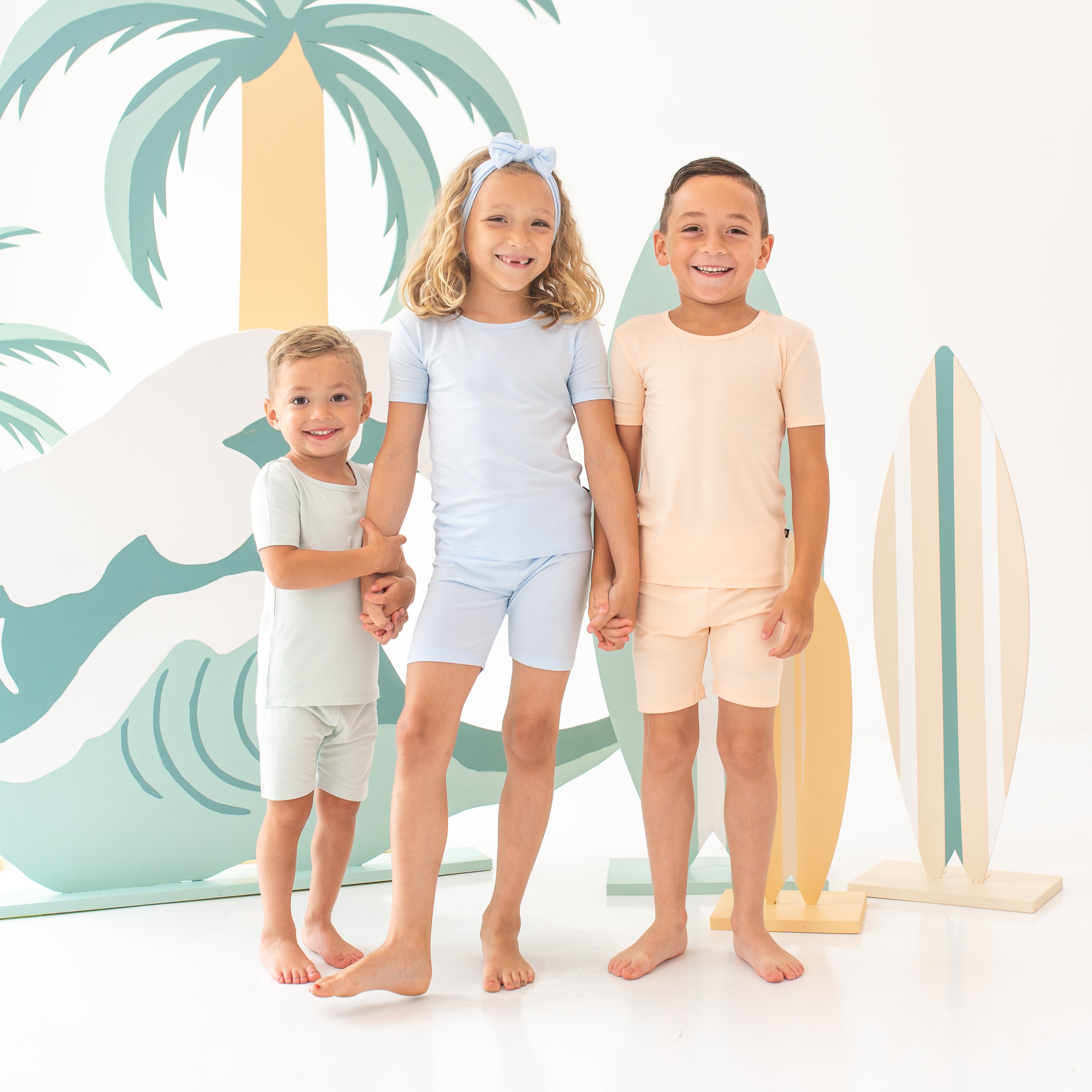 3 young models wearing the Toddler Short Sleeve Pajama set in the Summer Solid colors