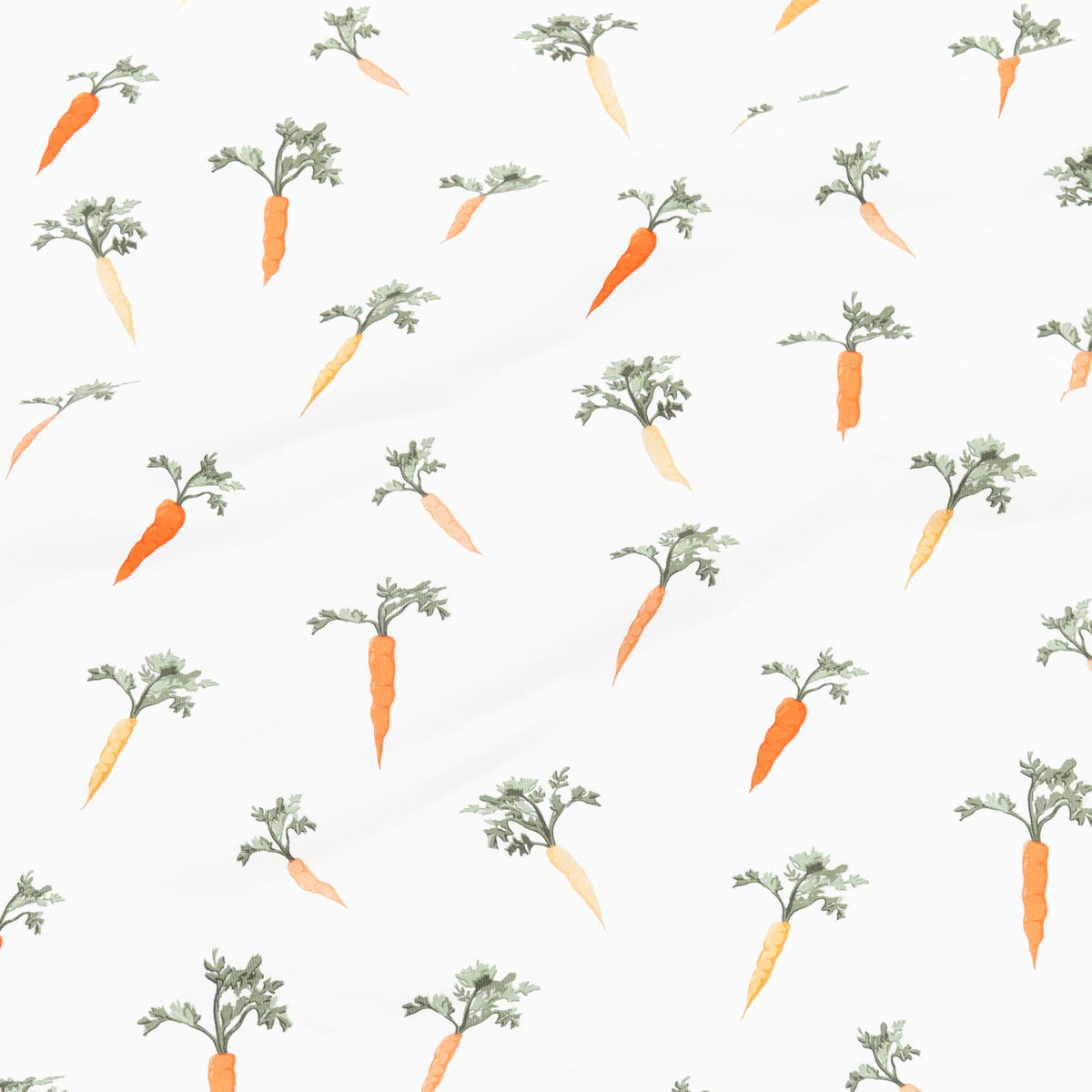 Close up of the fabric of the Carrot print showing the yellow and orange carrots with green stems on a white background