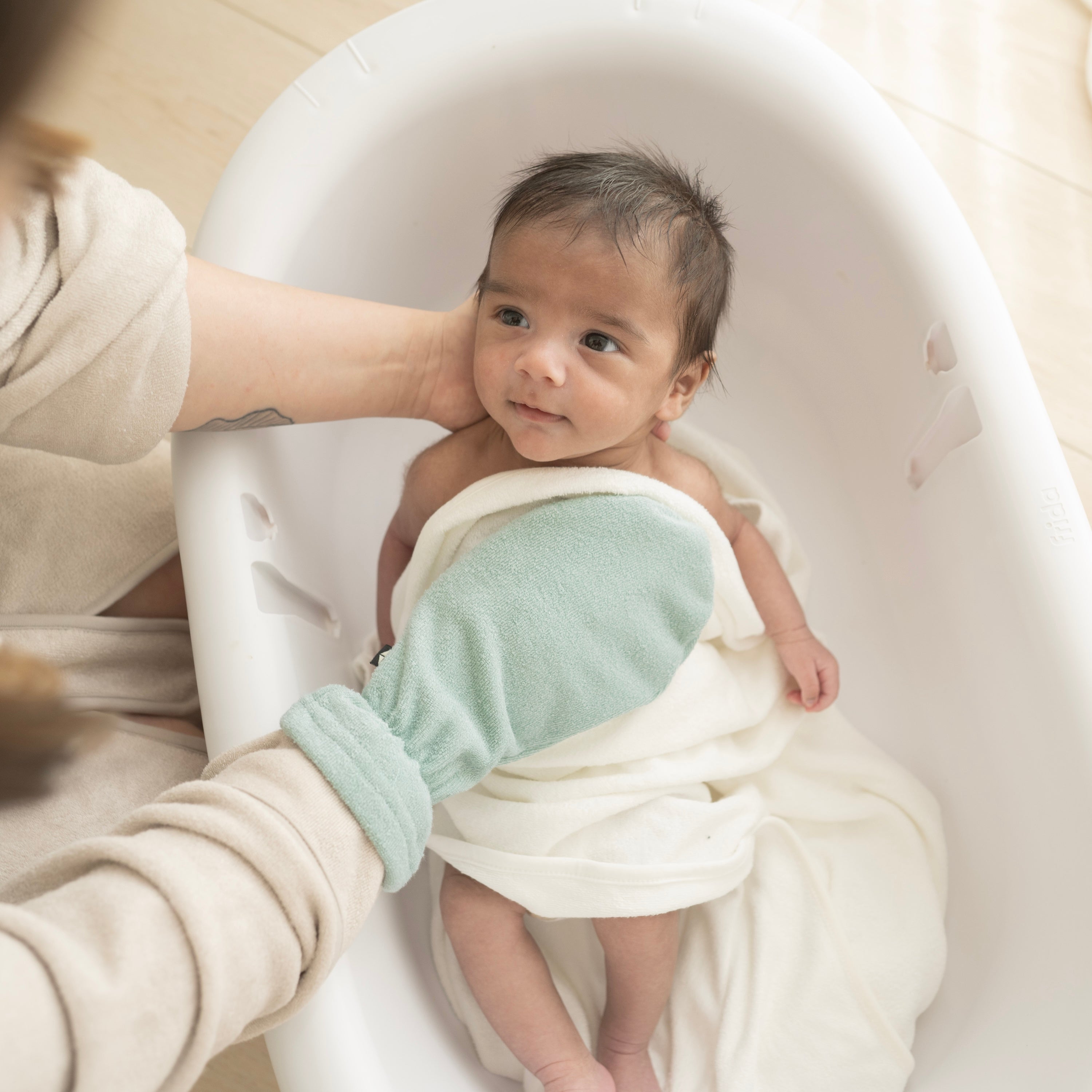 Parent bathing newborn with Terry Bath Mitt in Sage